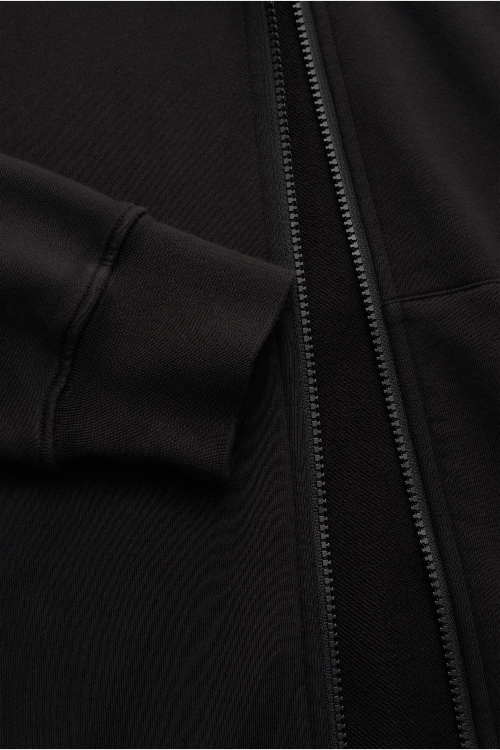 Nahaufnahme der Stone Island Sweatjacke schwarz von vorne mit geöffnetem robustem Reißverschluss, weichem Baumwollstoff und komfortablem Bündchen.