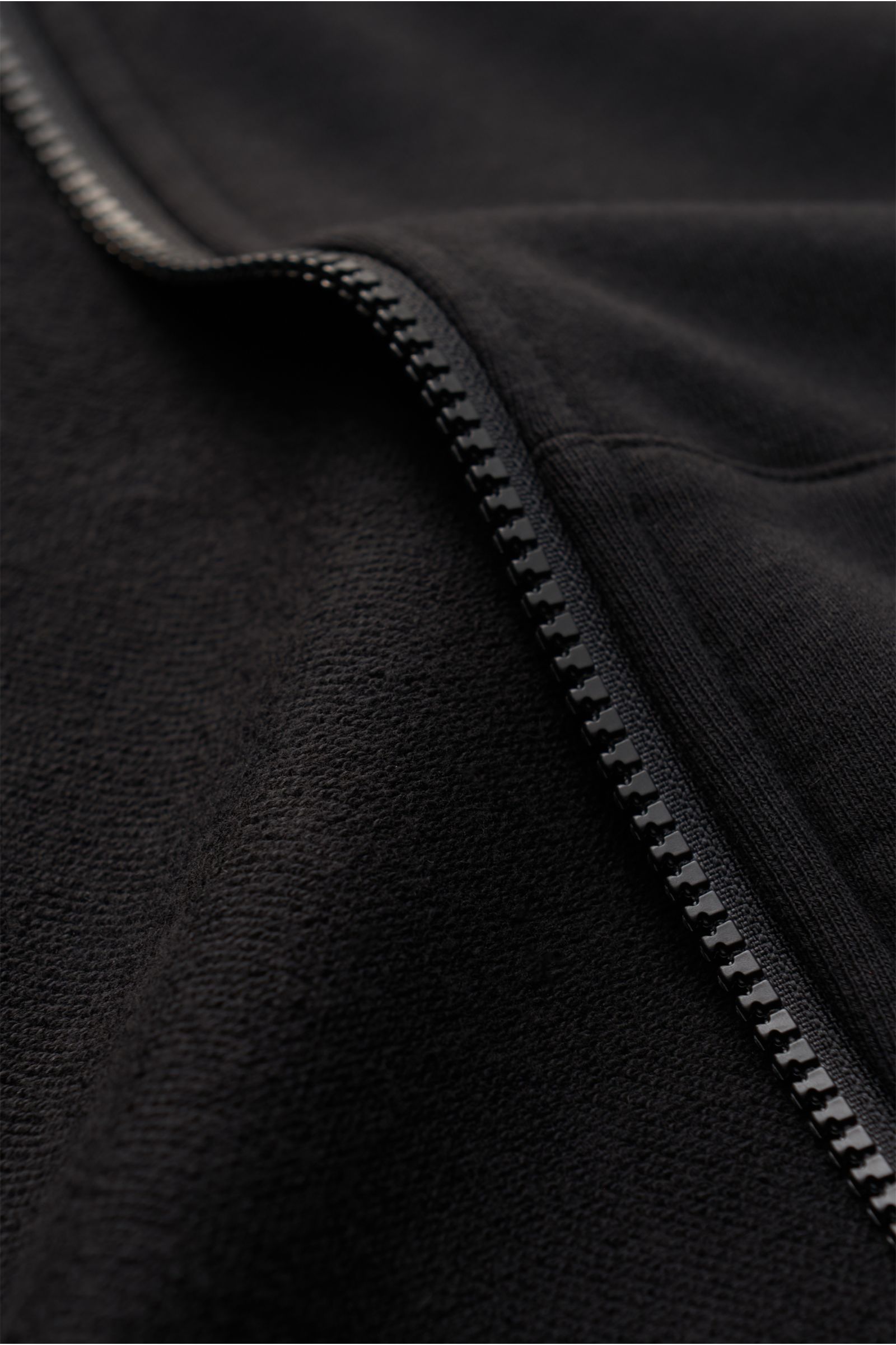 Nahaufnahme der Stone Island Sweatjacke schwarz, detailreicher Reißverschluss und weicher Baumwollstoff mit Kapuze, Slim Fit, Kompass-Badge.