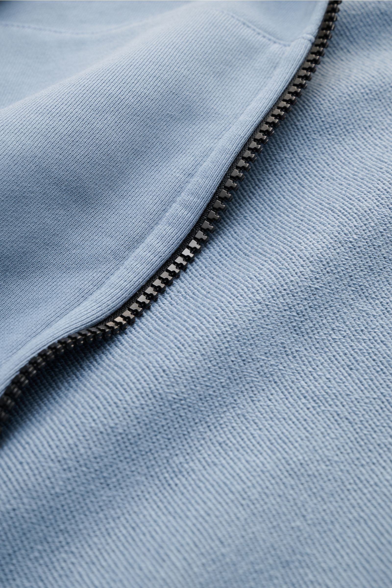 Close-up front view of the Stone Island Sweat jacket smoky blue showing soft cotton fabric and robust black zipper detail.

A relaxed basic from STONE ISLAND: This piece-dyed sweat jacket with a practical hood made of pure cotton is perfect for sport a