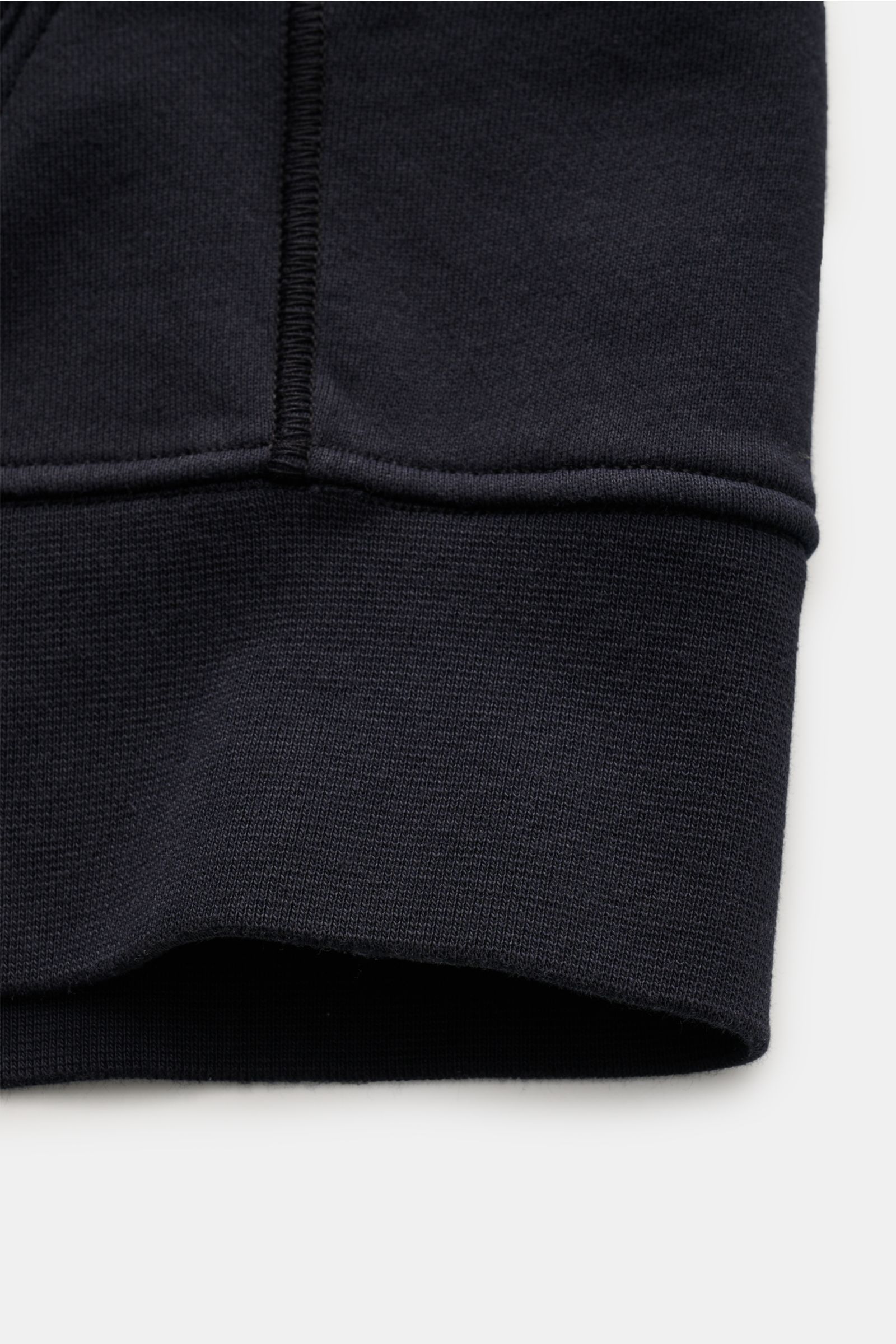 Detailaufnahme der Stone Island Sweatjacke dark navy mit weichem Rippbündchen, sportivem Basic aus garment dyed Baumwolle, seitliche Naht sichtbar.