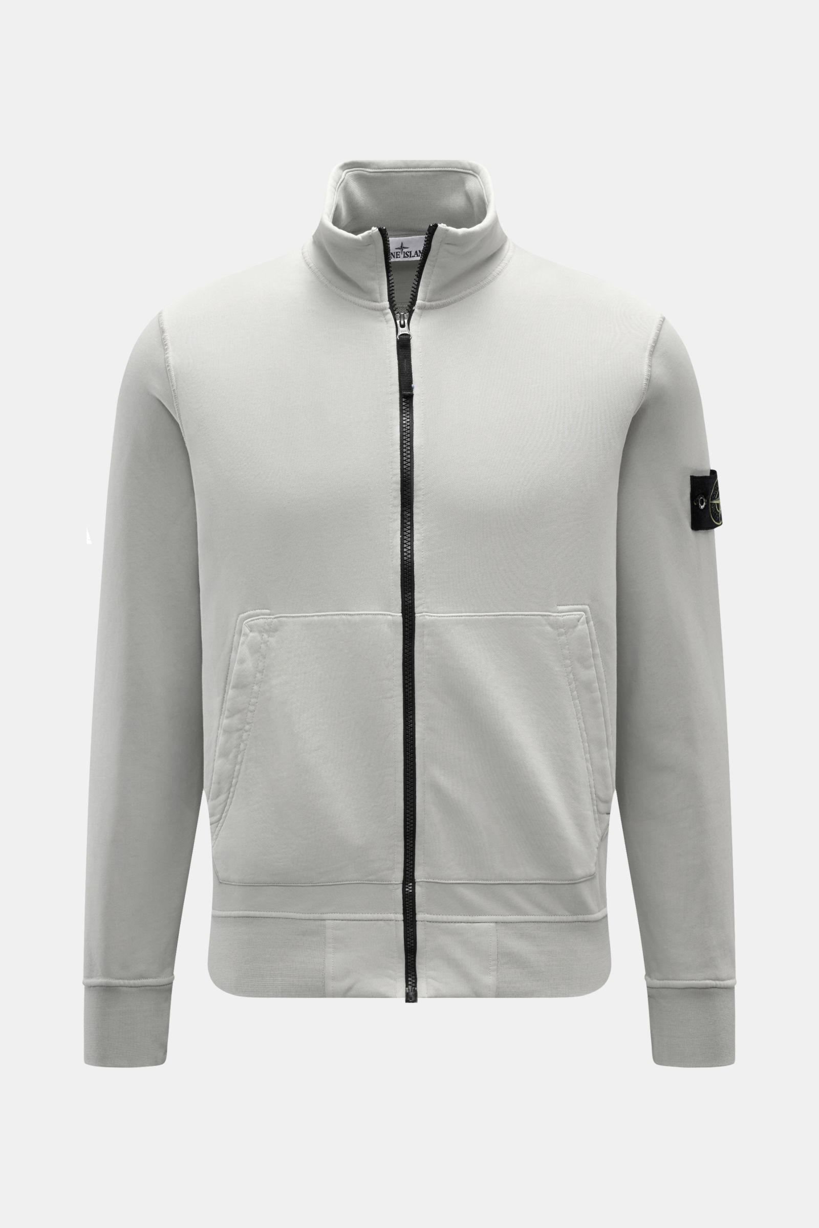 Front view of Stone Island Sweatjacke hellgrau, a light gray garment dyed cotton sweatshirt with a soft touch, regular fit, robust zipper, high collar, split kangaroo pocket, compass badge on the sleeve, and comfortable ribbed cuffs. 

Entspanntes Basi