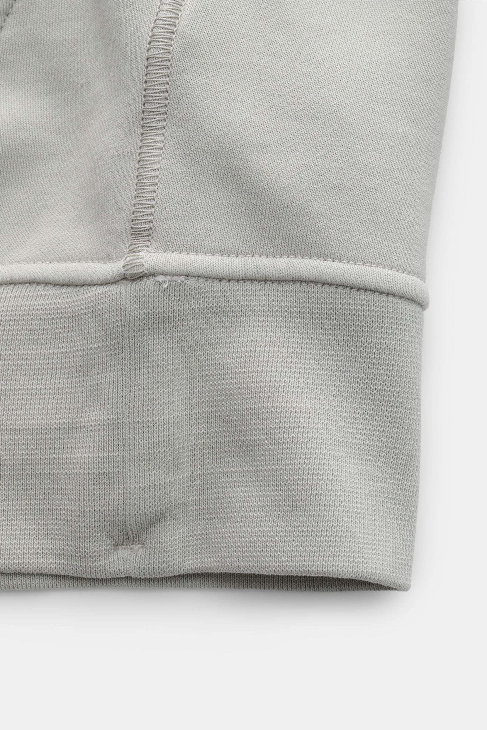 Stone Island Sweatjacke hellgrau, Detailaufnahme von unten, weicher Baumwoll-Sweat, garment dyed, Rippbündchen, robuste Nähte sichtbar.