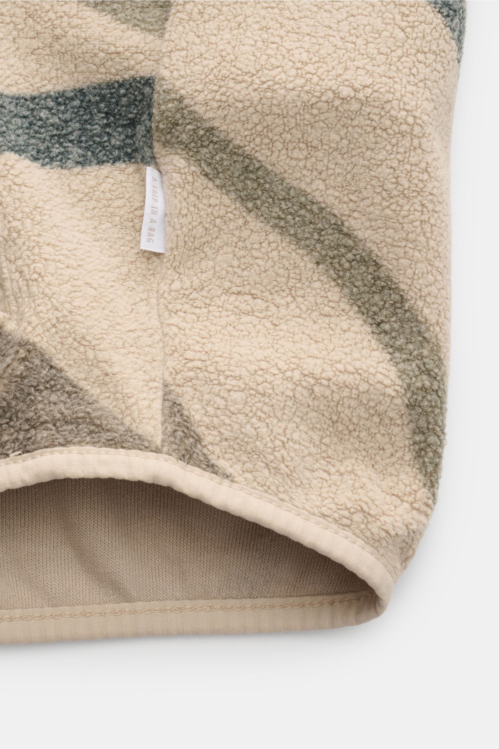 Close-up front bottom view of 04651/ A trip in a bag Fleece-Blouson schwarz showing fleece aus reiner Baumwolle, weicher Griff, Slim Fit, Druckknopfleiste, typischer Blousonkragen aus Rippstrick, schräge Hüfttaschen, komfortable Rippbündchen, and Weblabel