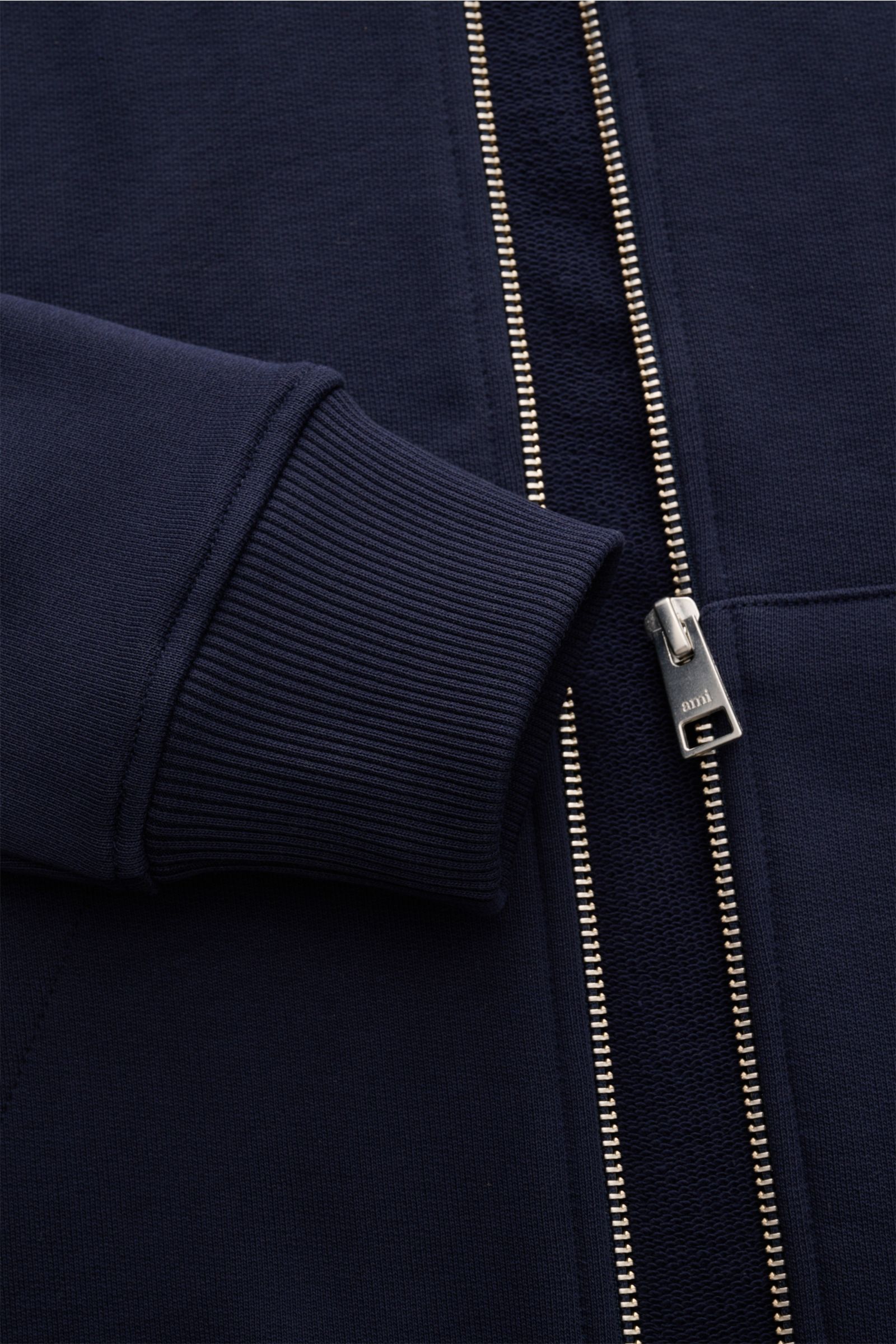 Nahaufnahme der Ami Paris Sweatjacke navy von vorne, zeigt Reißverschluss, Rippbündchen und Herz-Stitching auf Bio-Baumwolle.