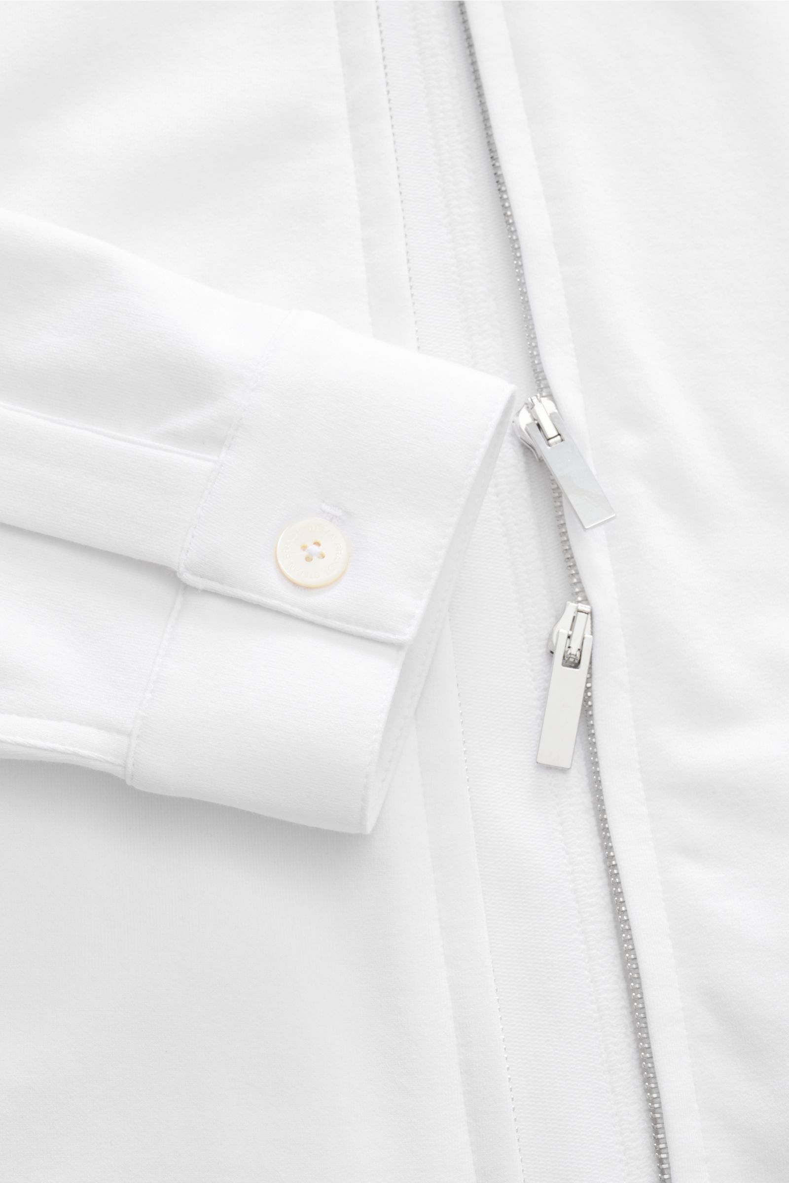 Close-up front view of Stefan Brandt Sweatjacke 'Alek' weiß showing white Pima cotton fabric, silver two-way zipper, and cuff with button; Spürbarer Komfort auf höchstem Niveau: Selbst ein Essential wie die Sweatjacke 'Alek' wird bei STEFAN BRANDT zum Aus