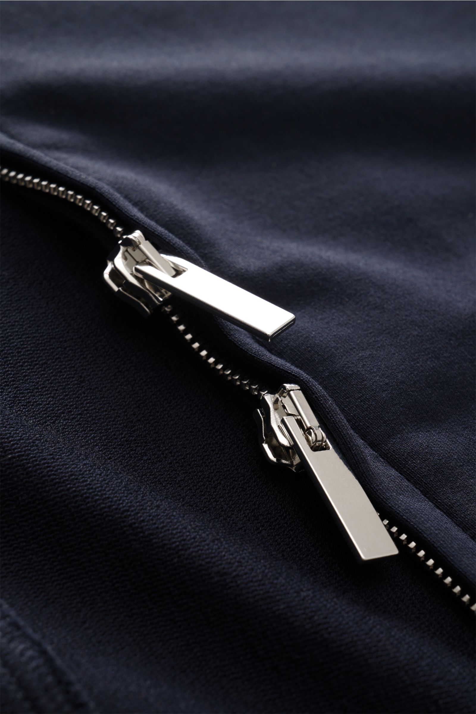 Close-up front view of the silver two-way zipper on the navy Stefan Brandt Sweatjacke 'Alek,' made from soft, lightweight Pima cotton fabric. Spürbarer Komfort auf höchstem Niveau: Selbst ein Essential wie die Sweatjacke 'Alek' wird bei STEFAN BRANDT zum 