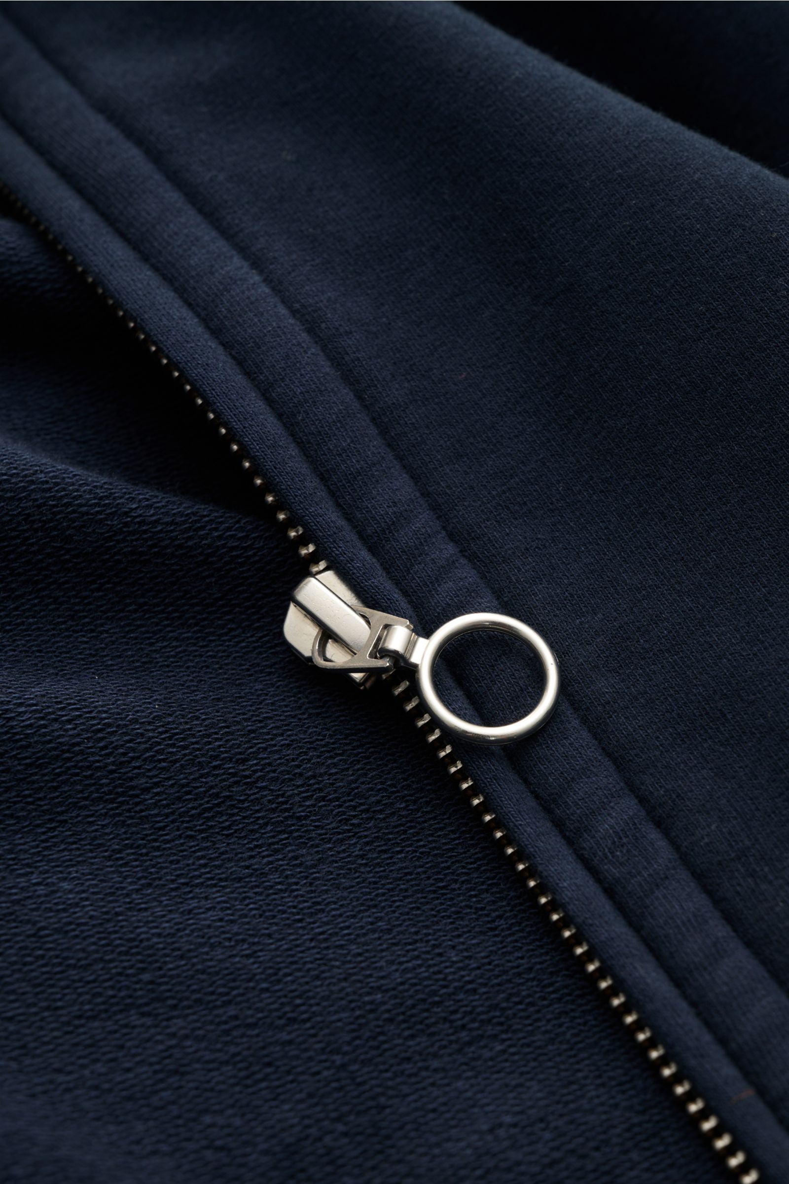 Nahaufnahme der silbernen Reißverschluss-Ziehschlaufe an der navy 04651/ A trip in a bag Sweatjacke 'IF Track' aus super softem elastischem Baumwoll-Jersey.