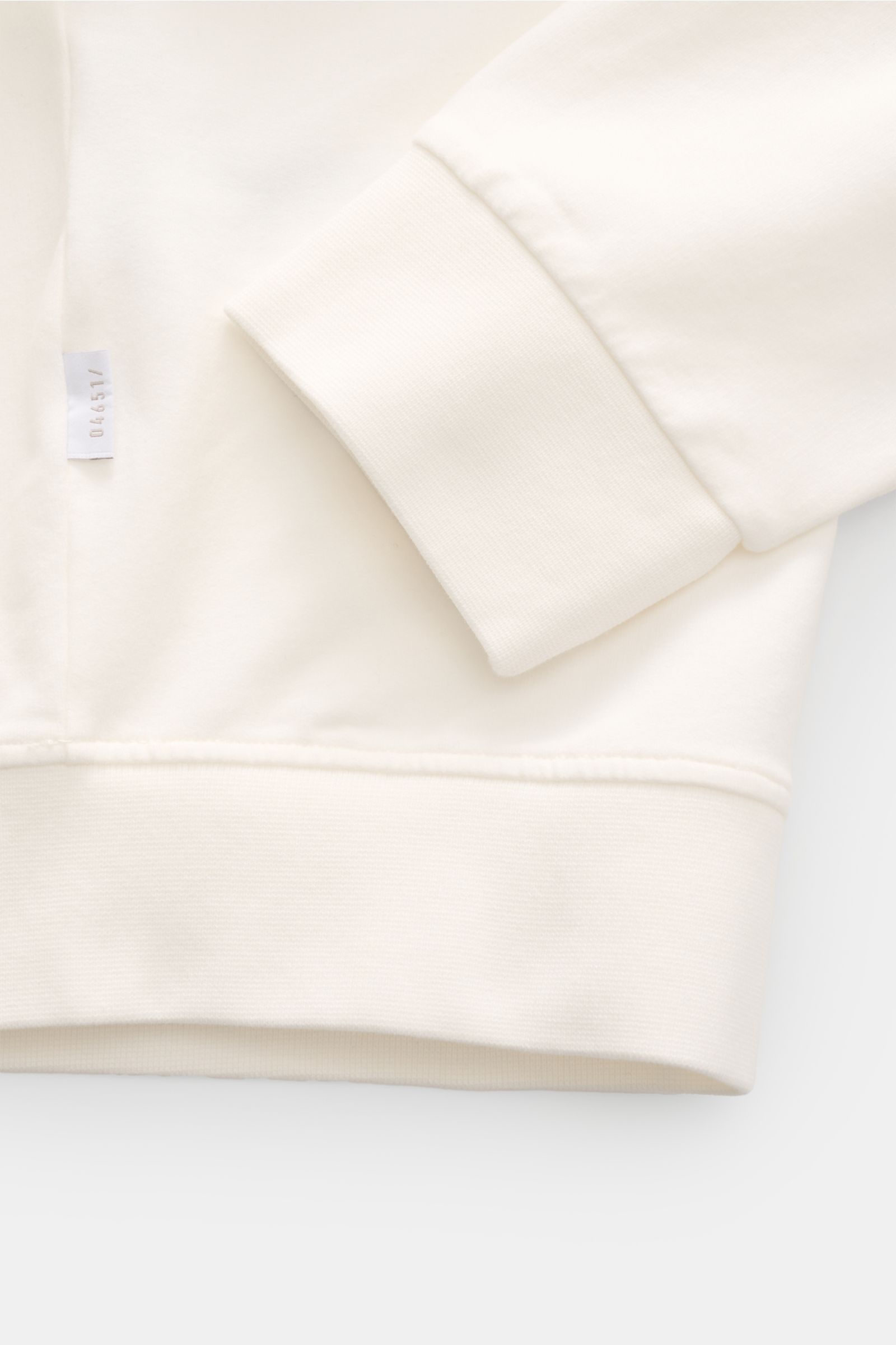 Close-up front view of the 04651/ A trip in a bag Sweat jacket 'IF Track' off-white showing ribbed cuff, waistband, and small woven label on soft cotton jersey fabric.
