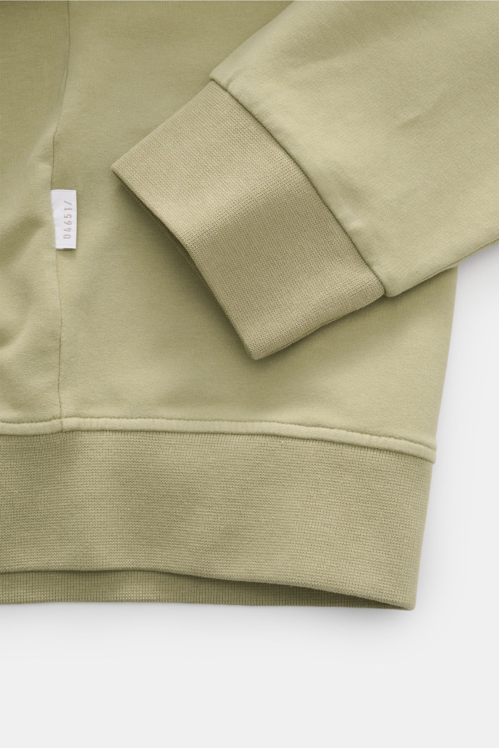 Nahaufnahme des Ärmels und Saums der 04651/ A trip in a bag Sweatjacke 'IF Track' salbei aus super softem, elastischem Baumwoll-Jersey mit flexiblem Rippbündchen und kleinem Weblabel.