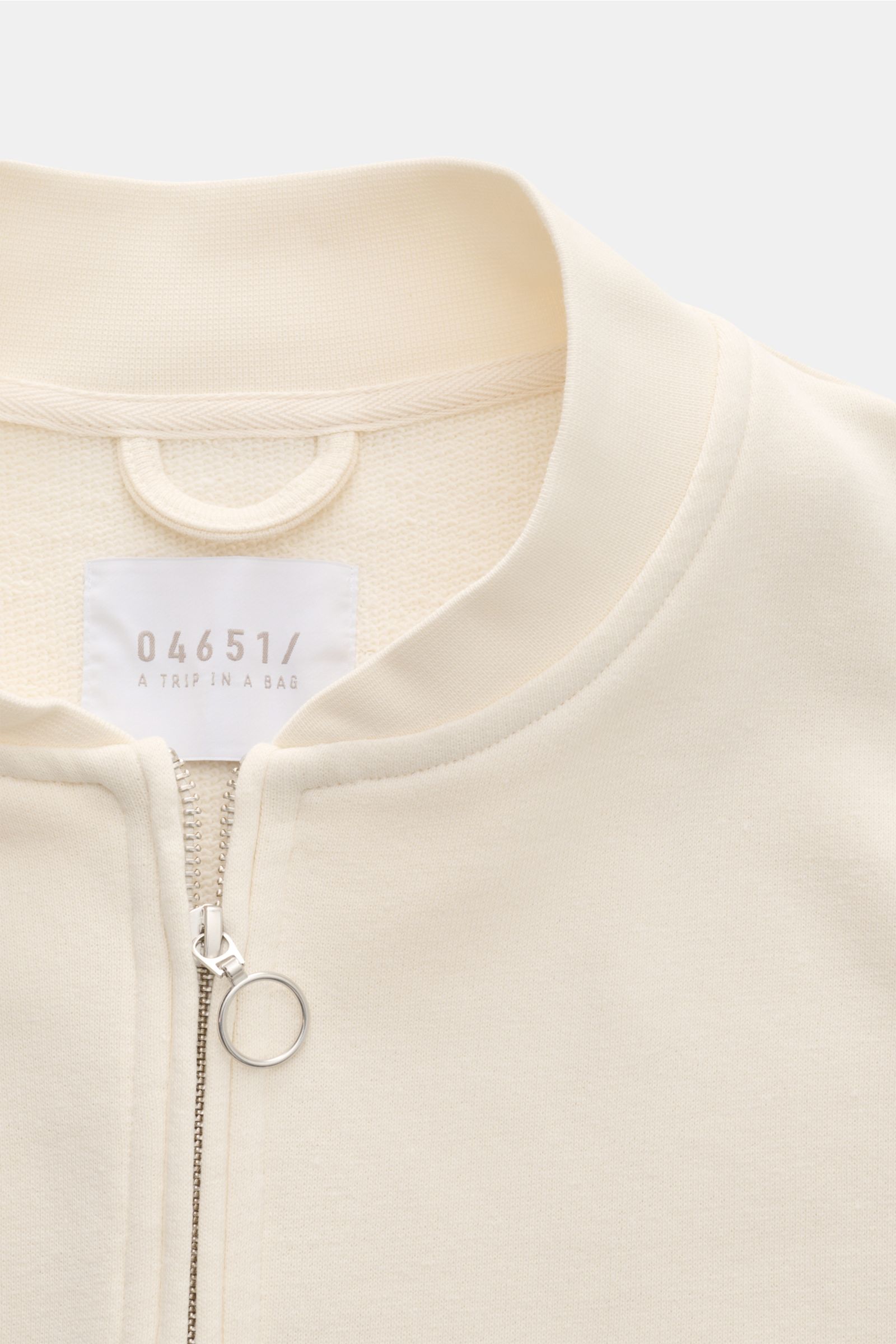 04651/ A trip in a bag Sweatjacke 'CL Bomber' creme, close-up von oben, Bio-Baumwolle-Leinen Mix, garment-dyed, robuster Zwei-Wege-Reißverschluss, Blousonkragen, Leistentaschen, Rippbündchen.