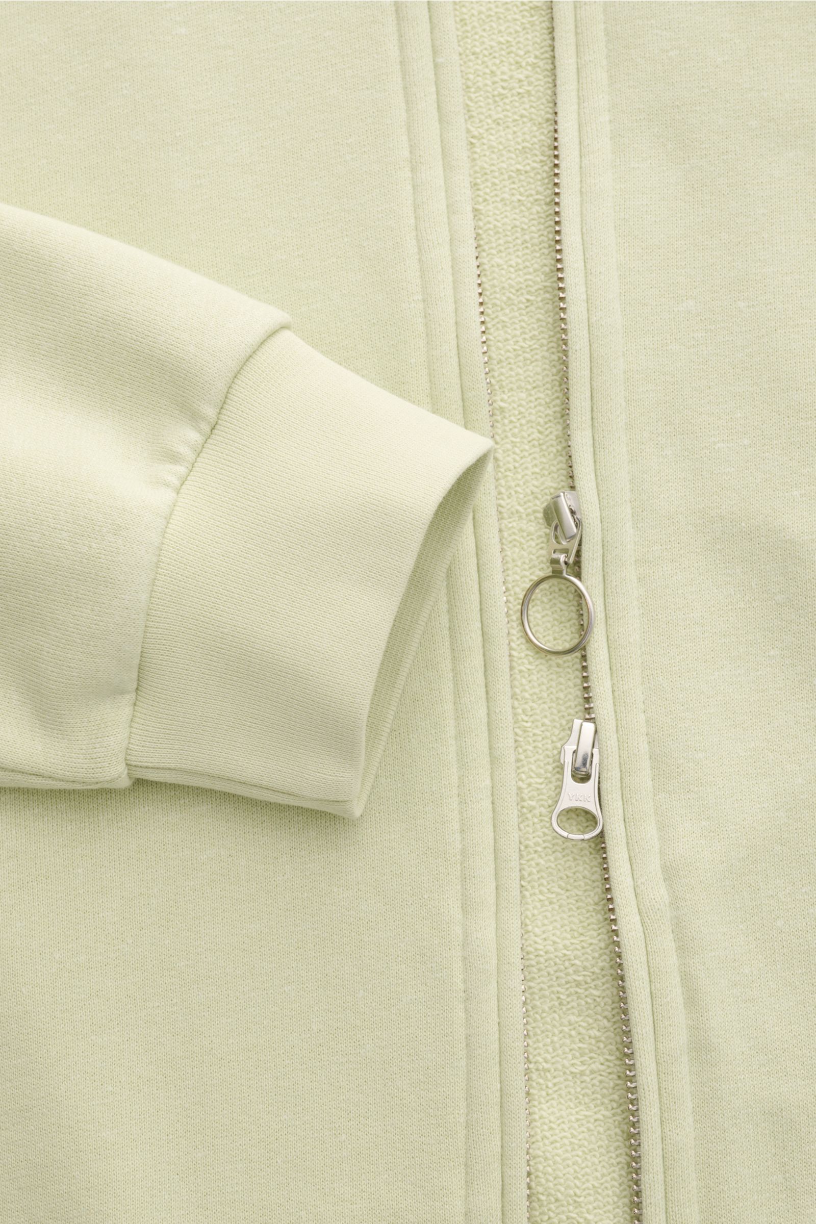 04651/ A trip in a bag Sweatjacke 'CL Bomber' pastellgrün, Nahaufnahme von Ärmel, Rippbündchen, Zwei-Wege-Reißverschluss und Stoffstruktur.