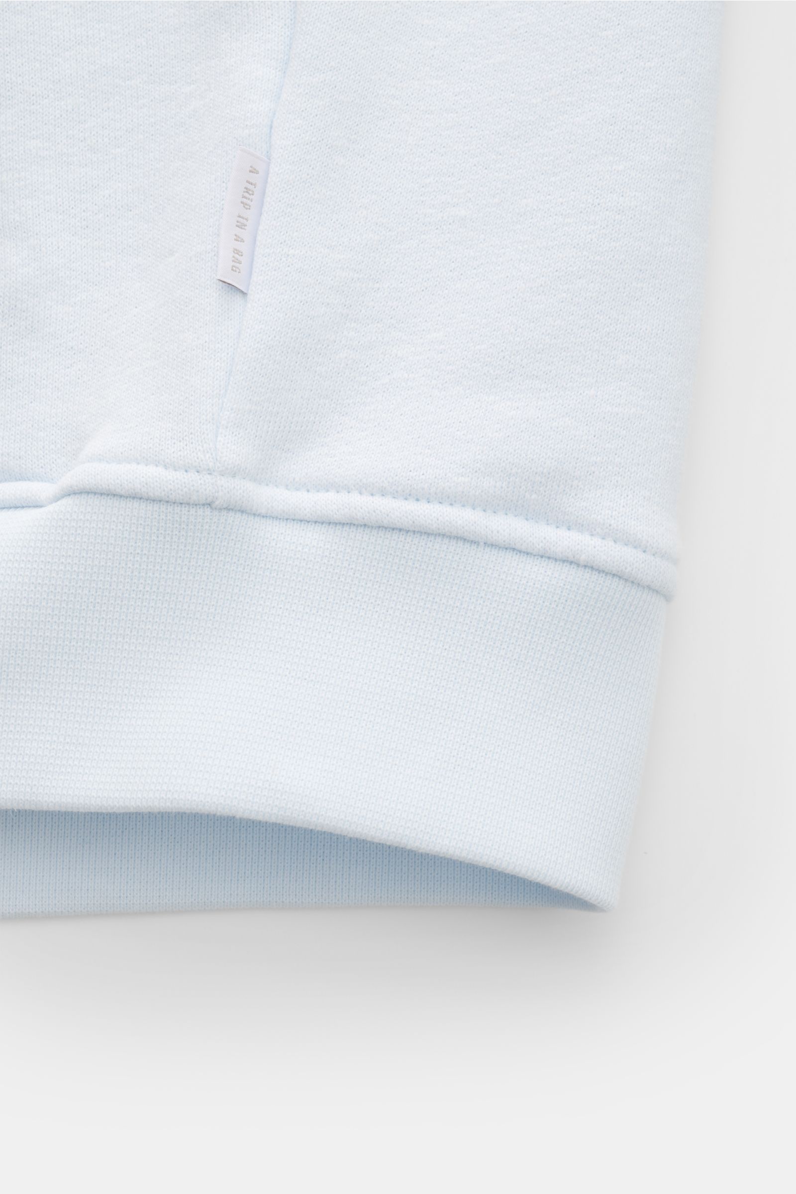 Leichtes Detailfoto der pastellblauen 04651/ A trip in a bag Sweatjacke 'CL Bomber' mit weichem Griff und Weblabel am Ärmelbündchen.