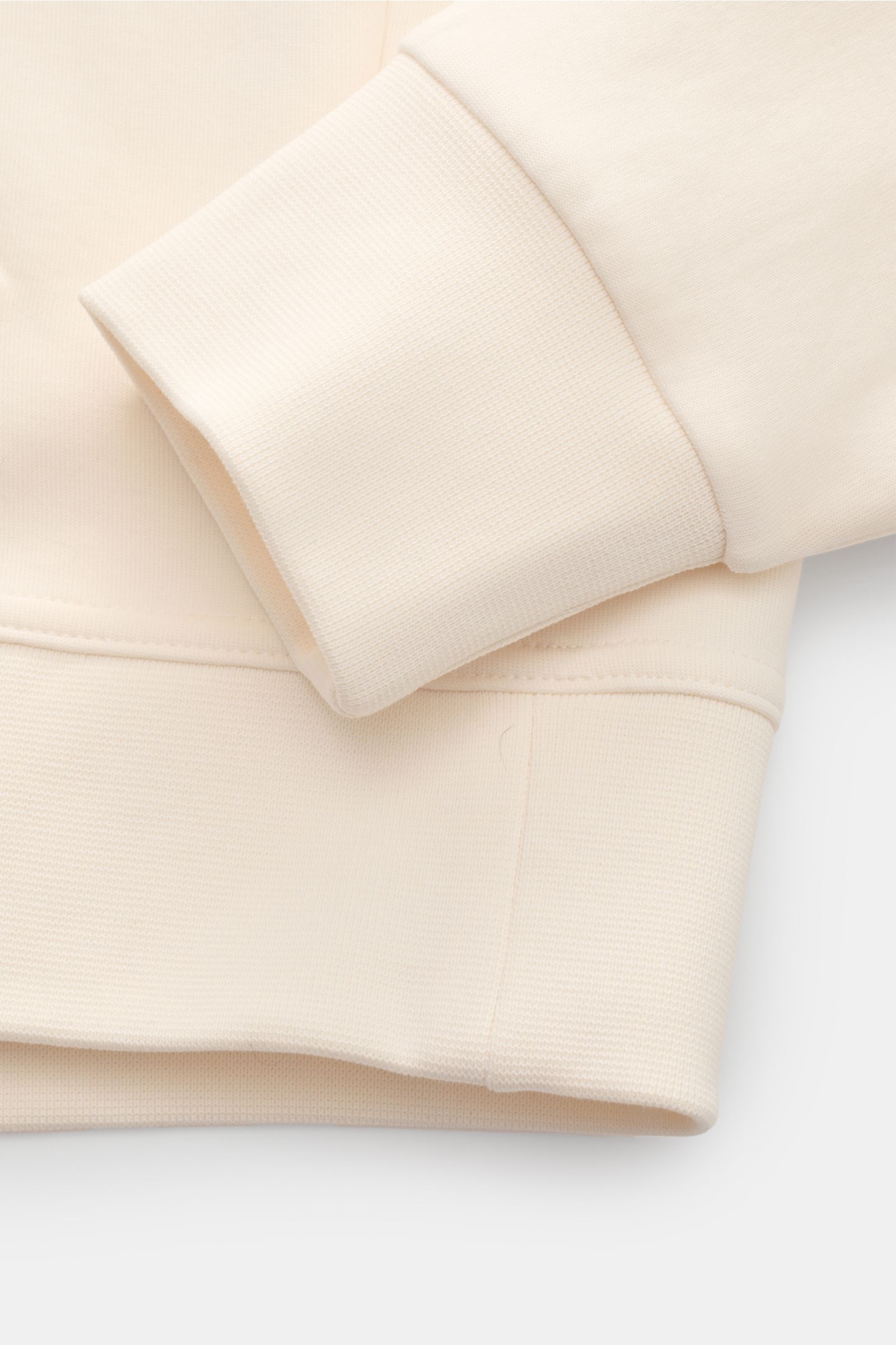 Nahaufnahme des Polo Ralph Lauren Kapuzenpullovers creme, Detailansicht von breiten Bündchen und Ärmeln, Jersey aus Baumwolle und Microfaser, weicher Griff, Regular Fit, Kapuze mit Tunnelzug, Kängurutasche, typisches Logo-Stitching.