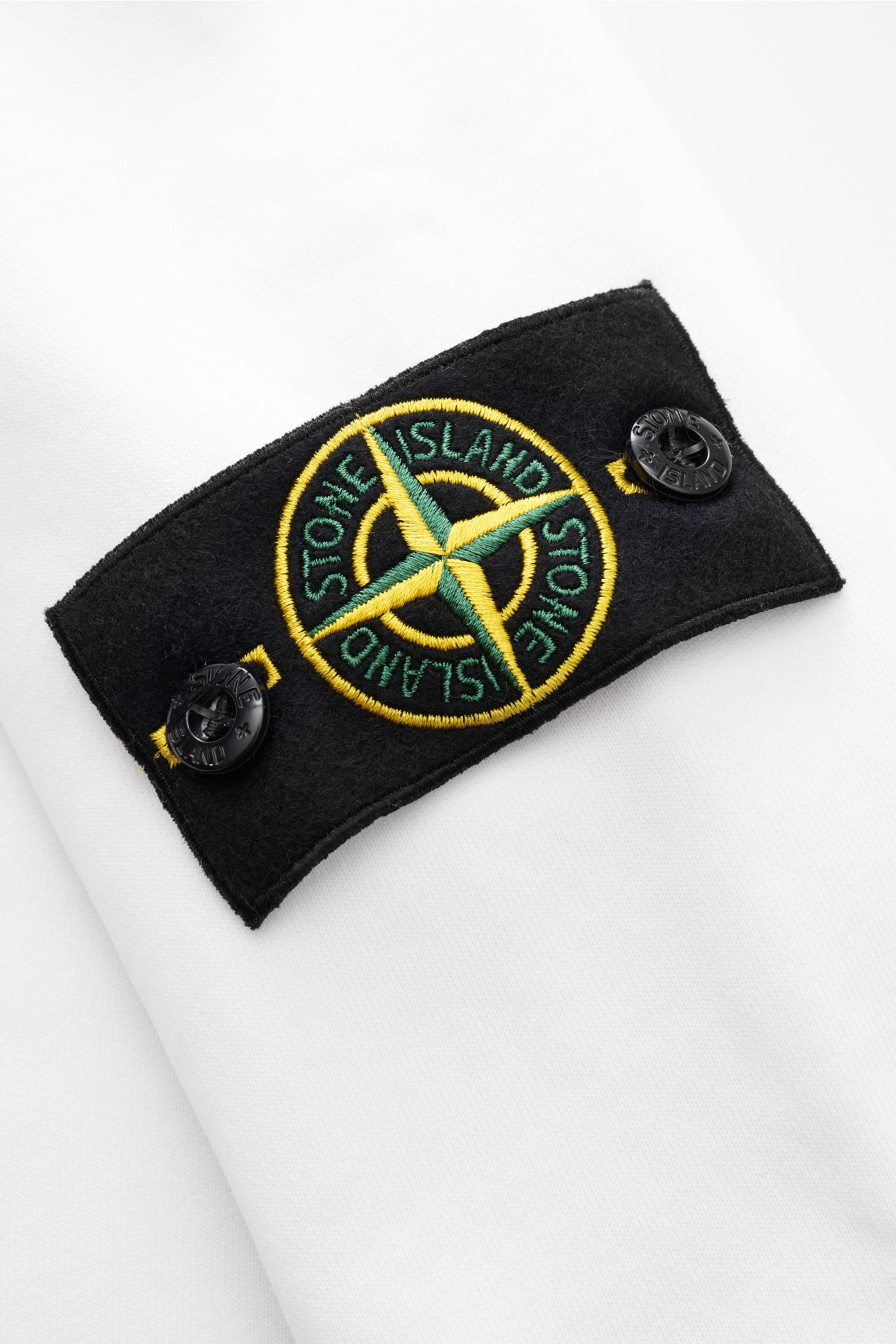 Stone Island Kapuzenpullover weiß aus reiner Baumwolle, weicher Griff, garment dyed, Regular Fit, Overlock-Nähte, Kapuze, Kompass-Badge am Ärmel, Kängurutasche, Rippbündchen, Detailaufnahme des Ärmel-Logos.