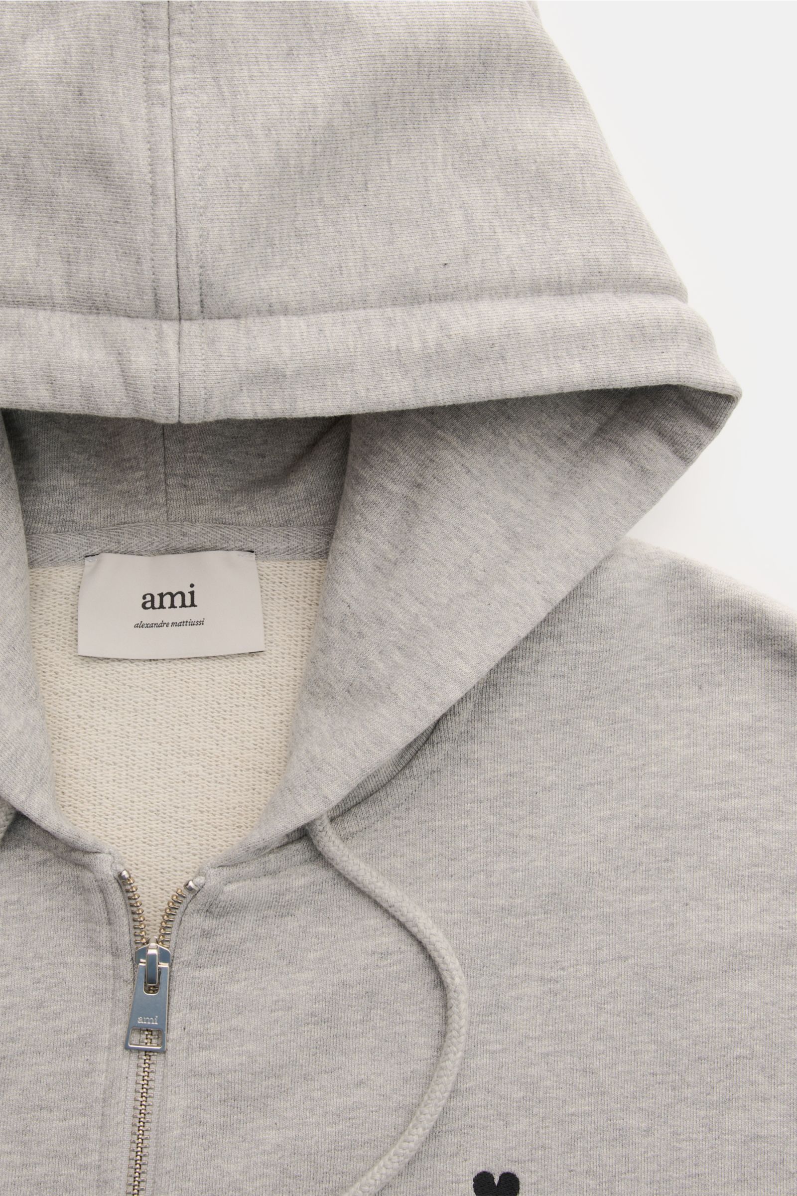 Ami Paris Sweatjacke hellgrau meliert shown from a close-up top-front view, featuring a hood with drawstrings, metal zipper, and subtle heart stitching on the chest. Ein dezentes Herz-Stitching auf der Brust verleiht dieser Baumwoll-Sweatjacke von AMI 