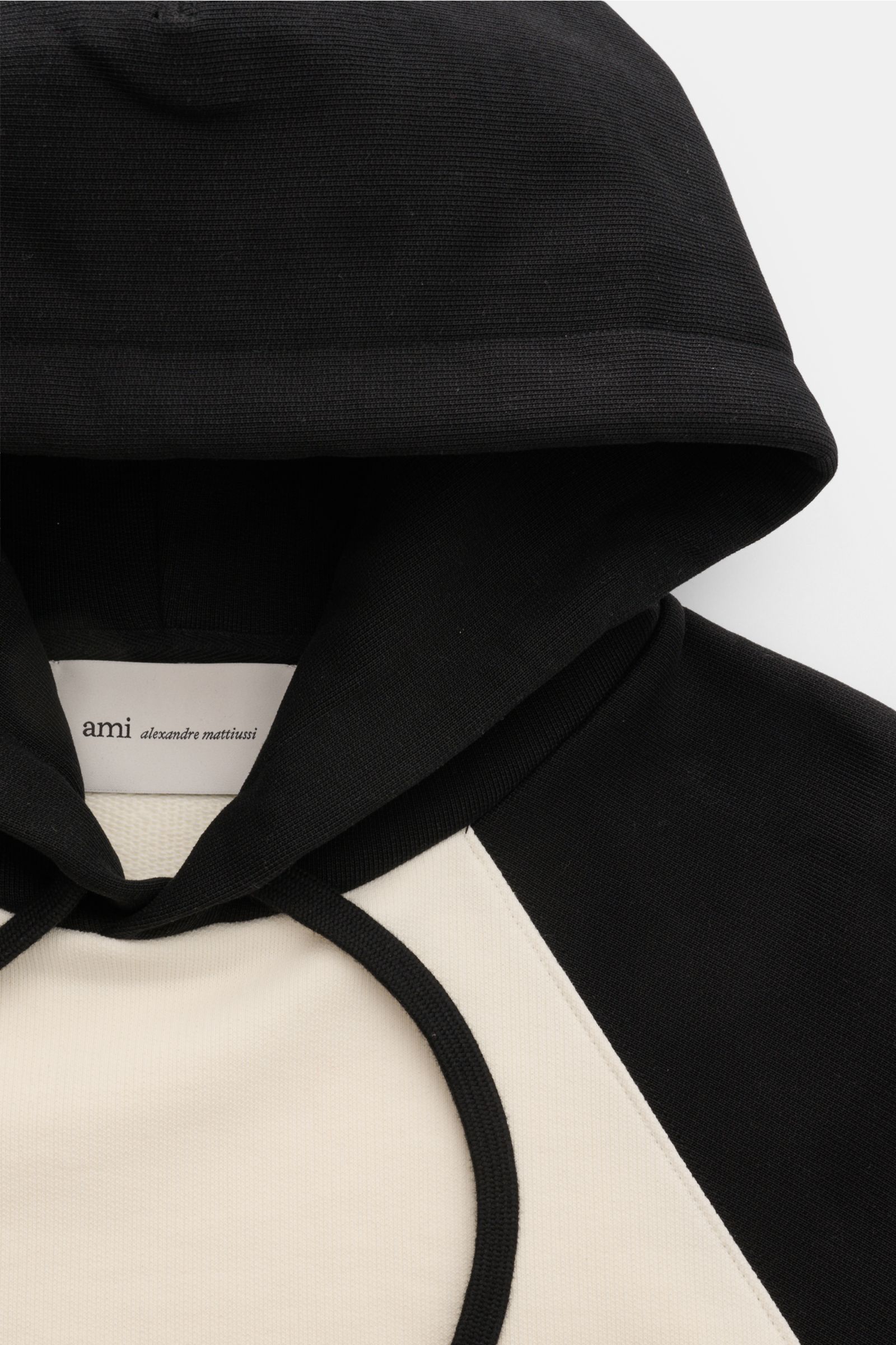 Ami Paris Kapuzenpullover 'Boxy Fit' creme/schwarz aus reiner Baumwolle, Raglanärmel, Kapuze mit Tunnelzug, Logo-Stitching, frontale Nahaufnahme.