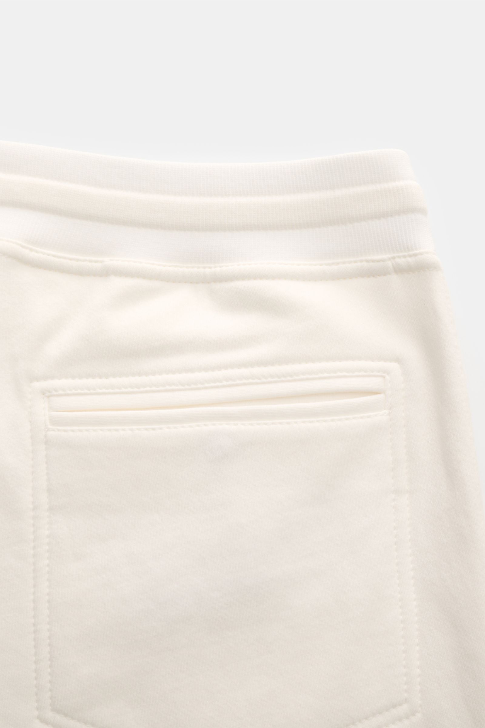 Brunello Cucinelli Sweathose offwhite shown from a close-up rear perspective, highlighting soft cotton-microfiber fabric, elastic waistband, tapered fit, angled welt pockets, and piped back patch pocket. Mit dieser komfortablen Sweathose kommen Sie gar
