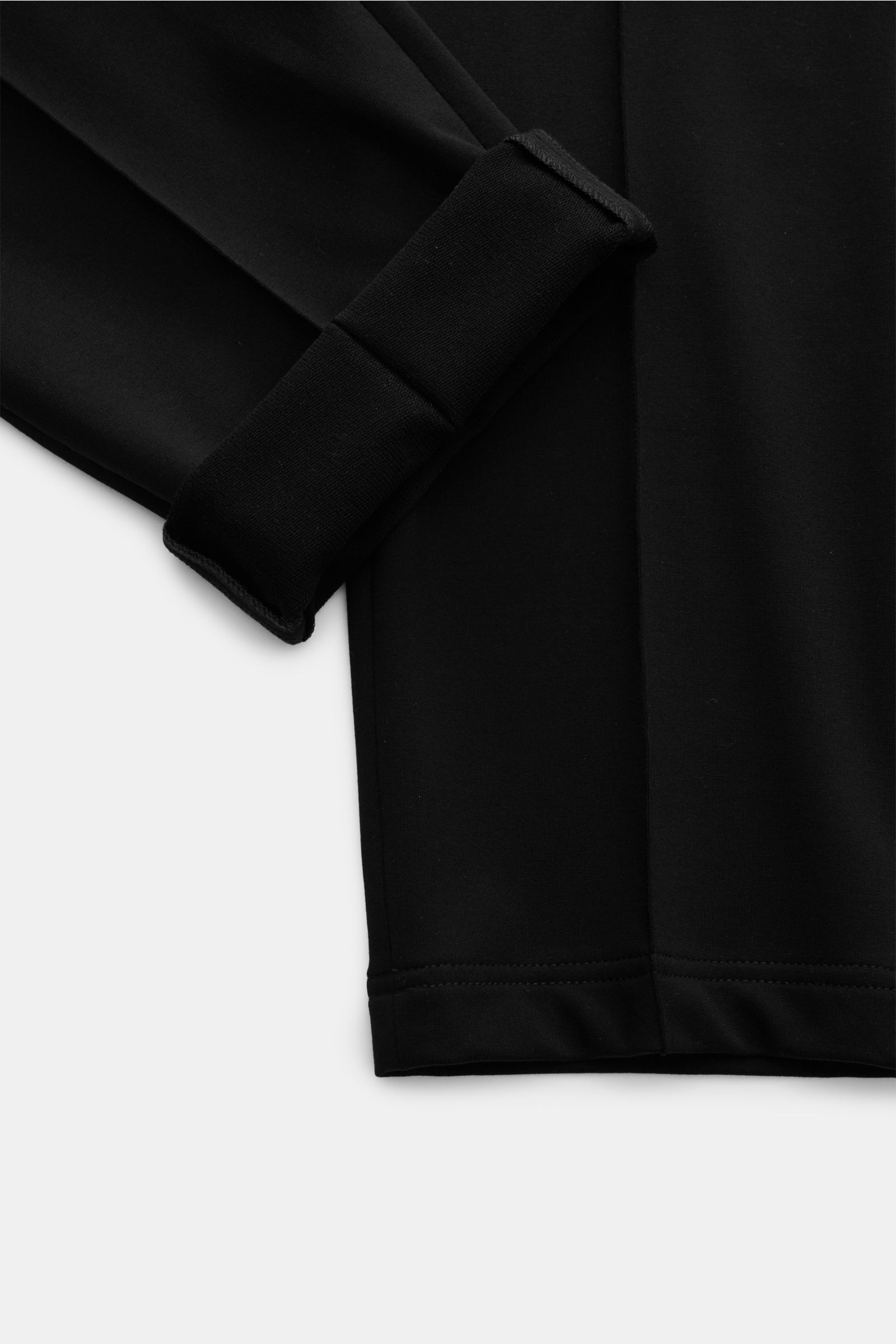 Nahaufnahme der schwarz gefalteten Stefan Brandt Sweathose 'Jonas' aus edler Pima Baumwolle mit Slim Fit, kurzem Schnitt, elastischem Bund und dekorativen Biesen.