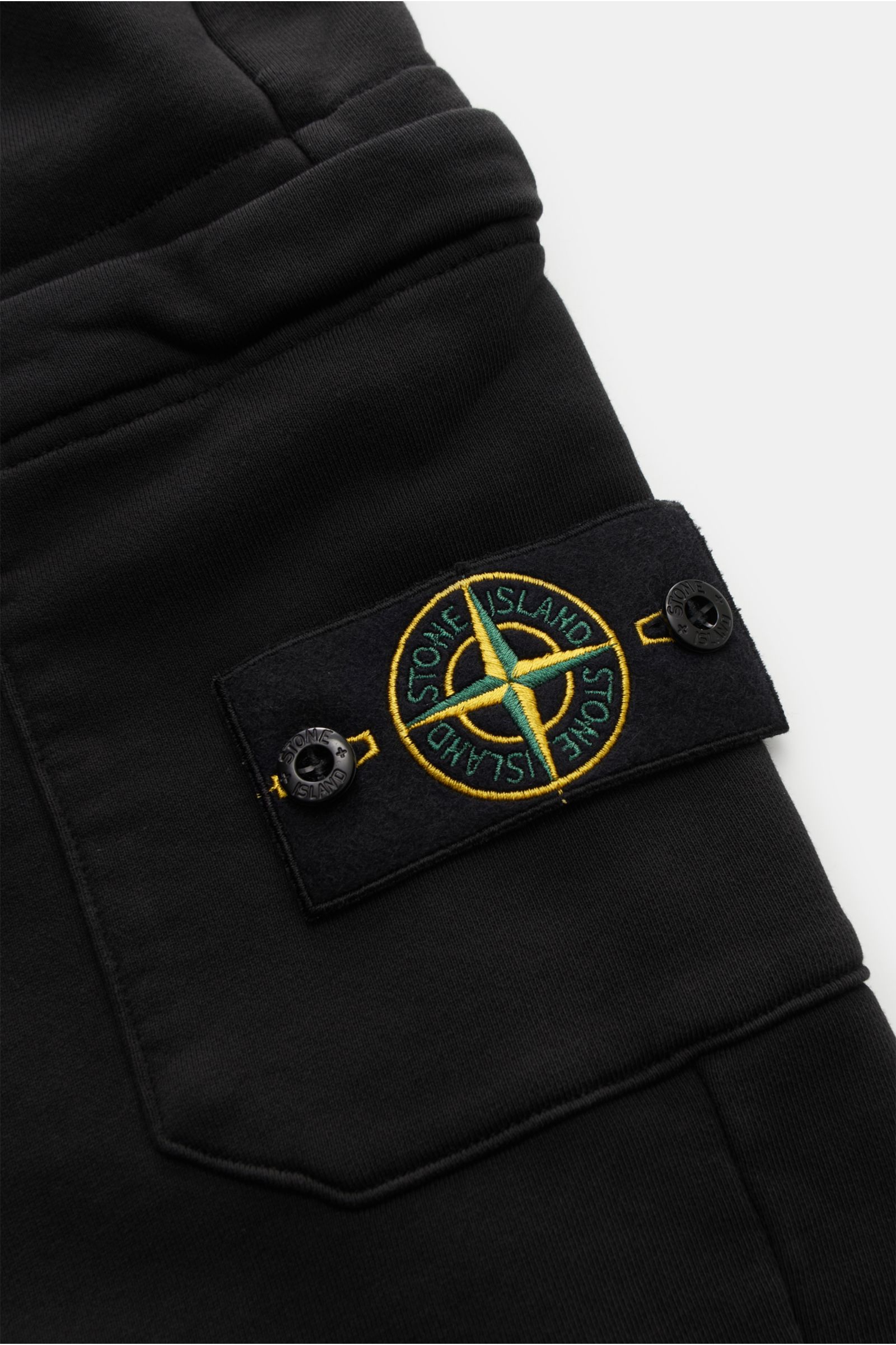 Nahaufnahme der schwarzen Stone Island Cargo-Sweatpants mit elastischem Bund, Cargo-Tasche und Kompass-Badge, seitliche Perspektive.