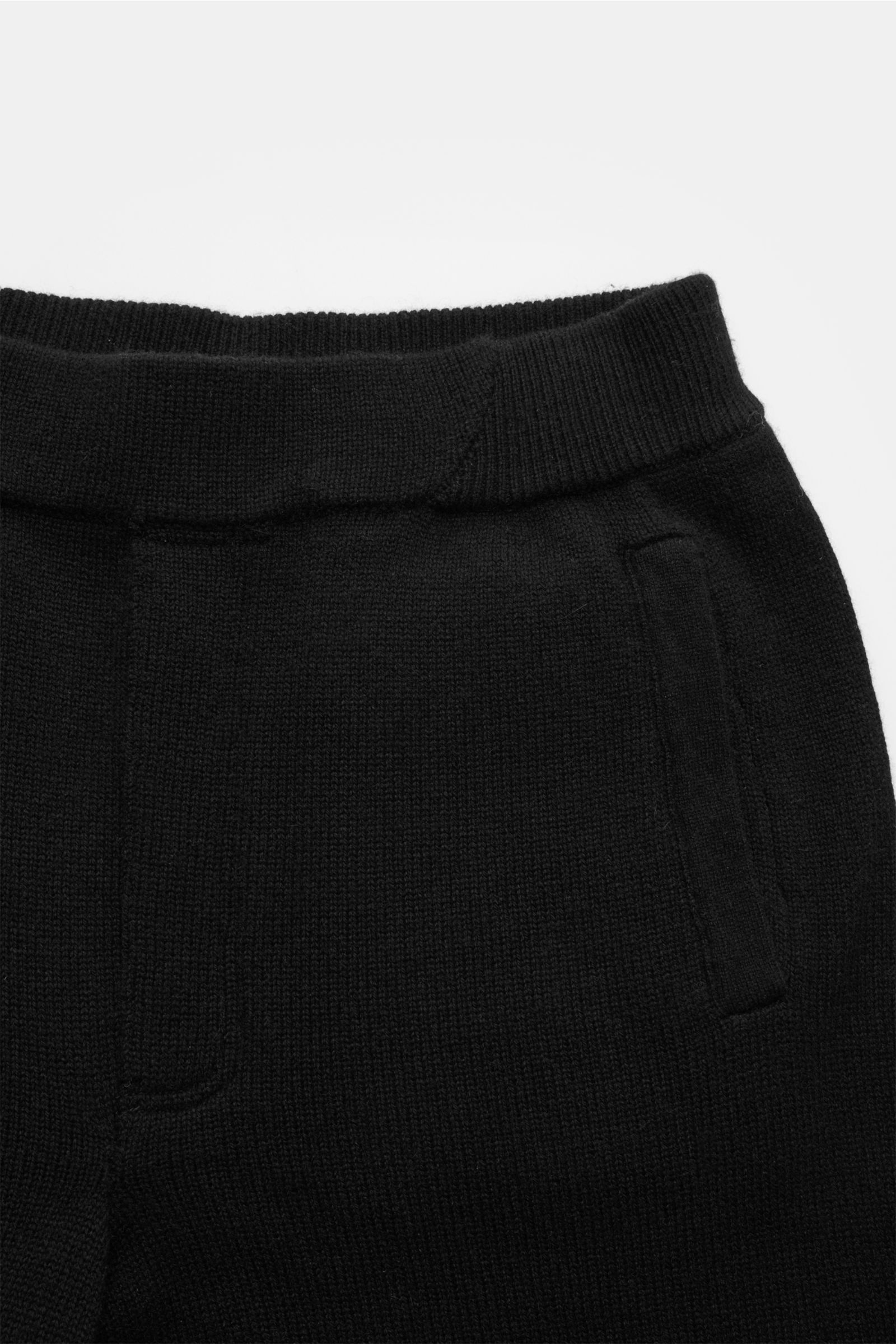 Nahaufnahme der von Braun Cashmere Jogpants schwarz aus geradem Schnitt, weichem, mongolischem Cashmere mit elastischem Bund, angedeutetem Eingriff, schrägen Hüfttaschen und Leistentaschen am Gesäß, fotografiert von oben.