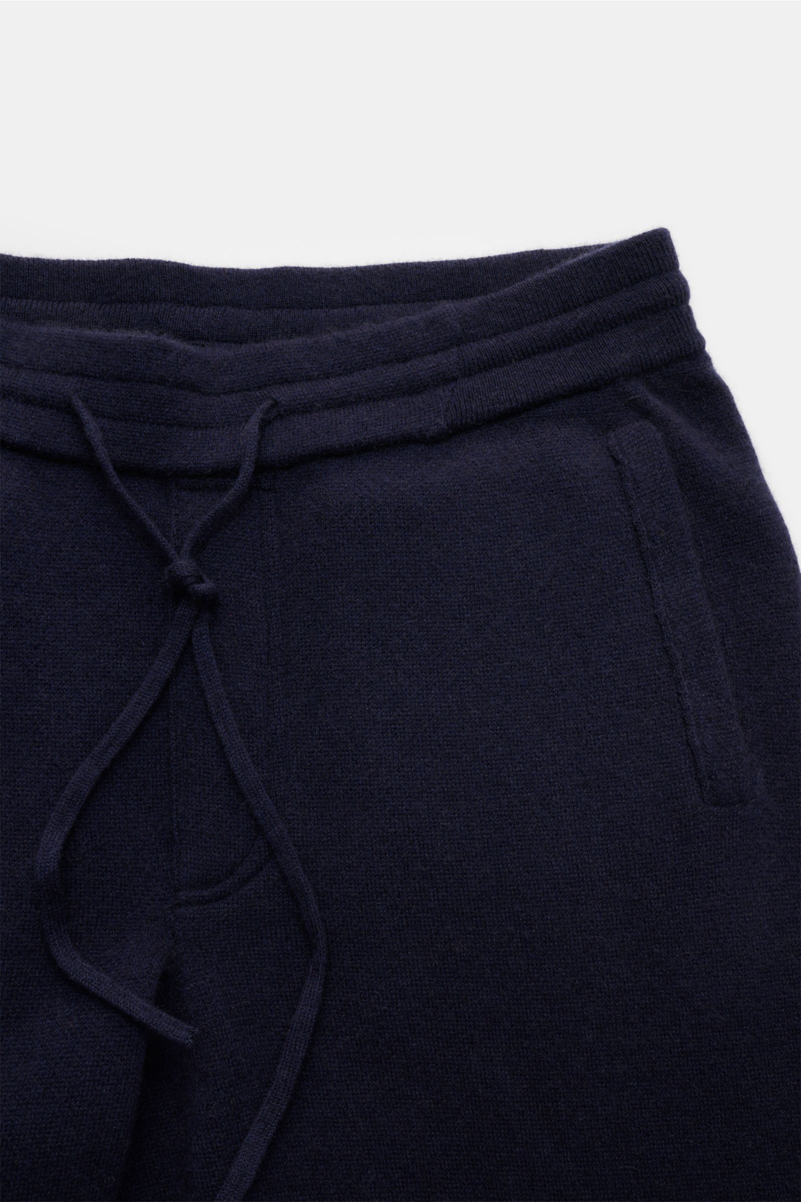 Nahaufnahme von der Taille einer von Braun Cashmere Jogpants navy, aus weichem, feinem Cashmere mit elastischem Bund, Tunnelzug, angedeutetem Eingriff und schrägen Hüfttaschen, fotografiert von oben.