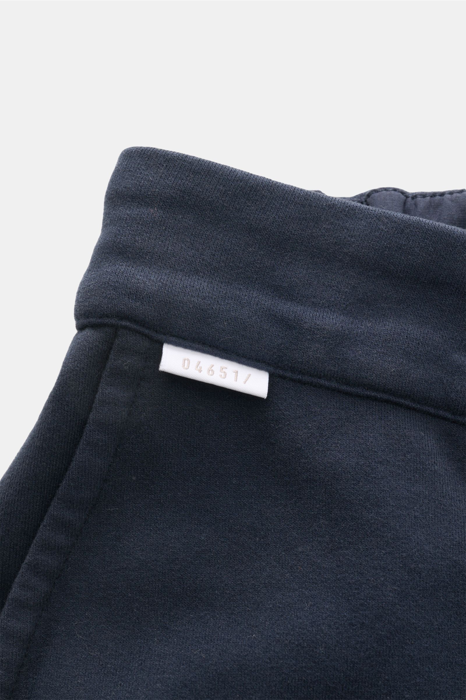 Close-up photo from a top angle of the waistband and label of 04651/ A trip in a bag Jogger pants 'If' navy in soft cotton jersey fabric, showing fine stitching and texture.

Description to include:
Comfort meets style: These jogger pants in soft cotto