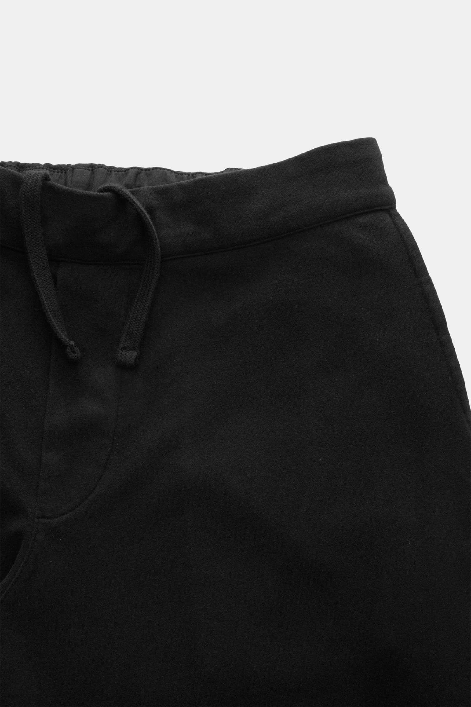 Black cotton jersey jogger pants viewed from above, showing waistband, drawstring, and partial front details. Comfort meets style: These jogger pants in soft cotton jersey by 04651/ A TRIP IN A BAG enhance relaxed looks with a modern silhouette. Jersey ma