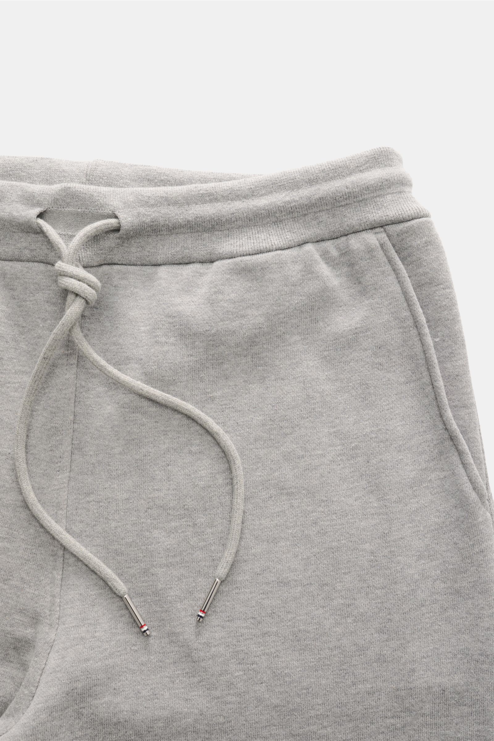 Thom Browne Sweathose grau meliert aus reiner Baumwolle, Slim Fit, elastischer Bund mit Tunnelzug, Perspektive von oben auf Bund und Taschen.