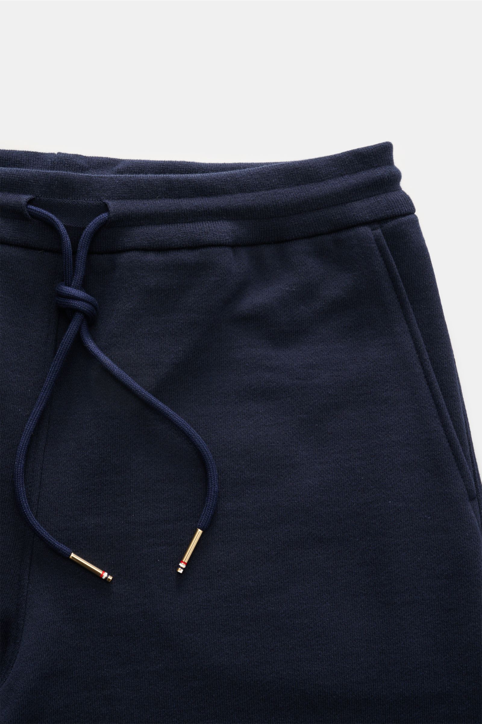 Nahaufnahme der Thom Browne Sweathose navy aus weicher, reiner Baumwolle, slim Fit mit elastischem Bund und markentypischem Streifen-Detail.