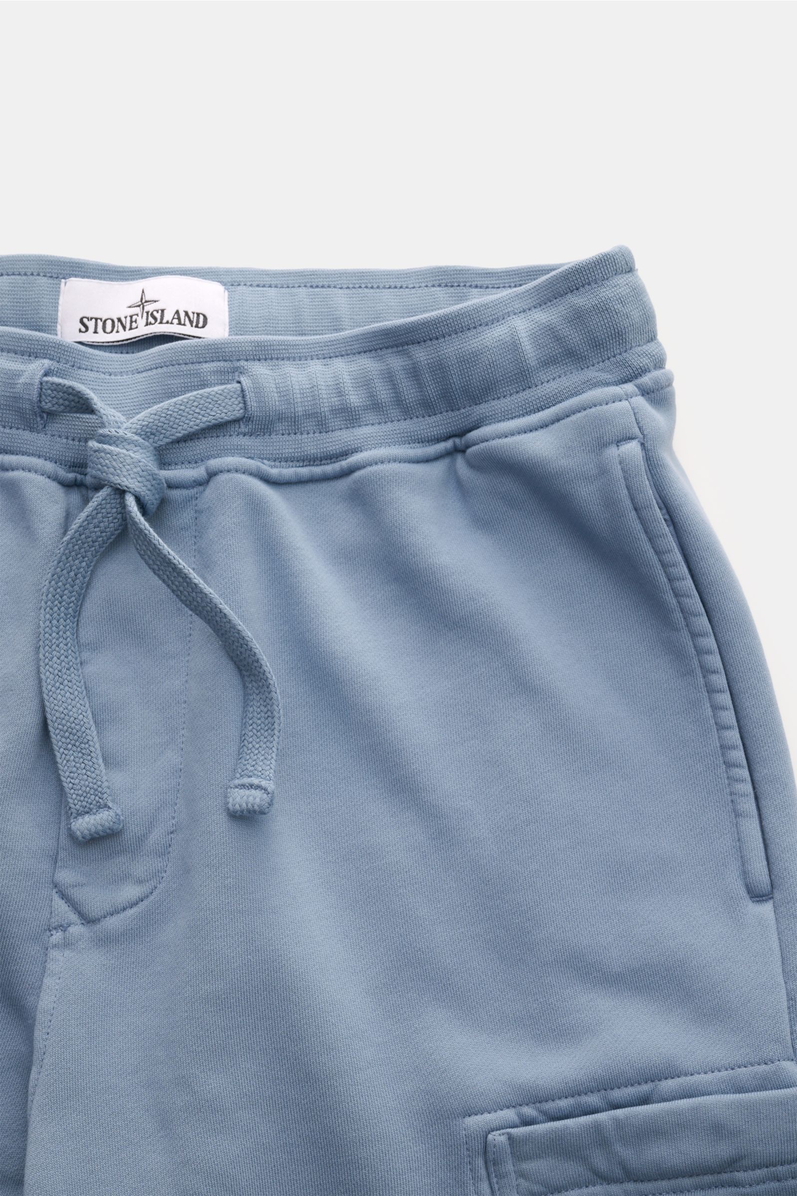 Stone Island Sweatshorts 'Basic Sweat' rauchblau, Detailaufnahme von oben, weicher Bio-Baumwollstoff, elastischer Bund mit Tunnelzug, Reißverschlusstasche und Cargo-Tasche.