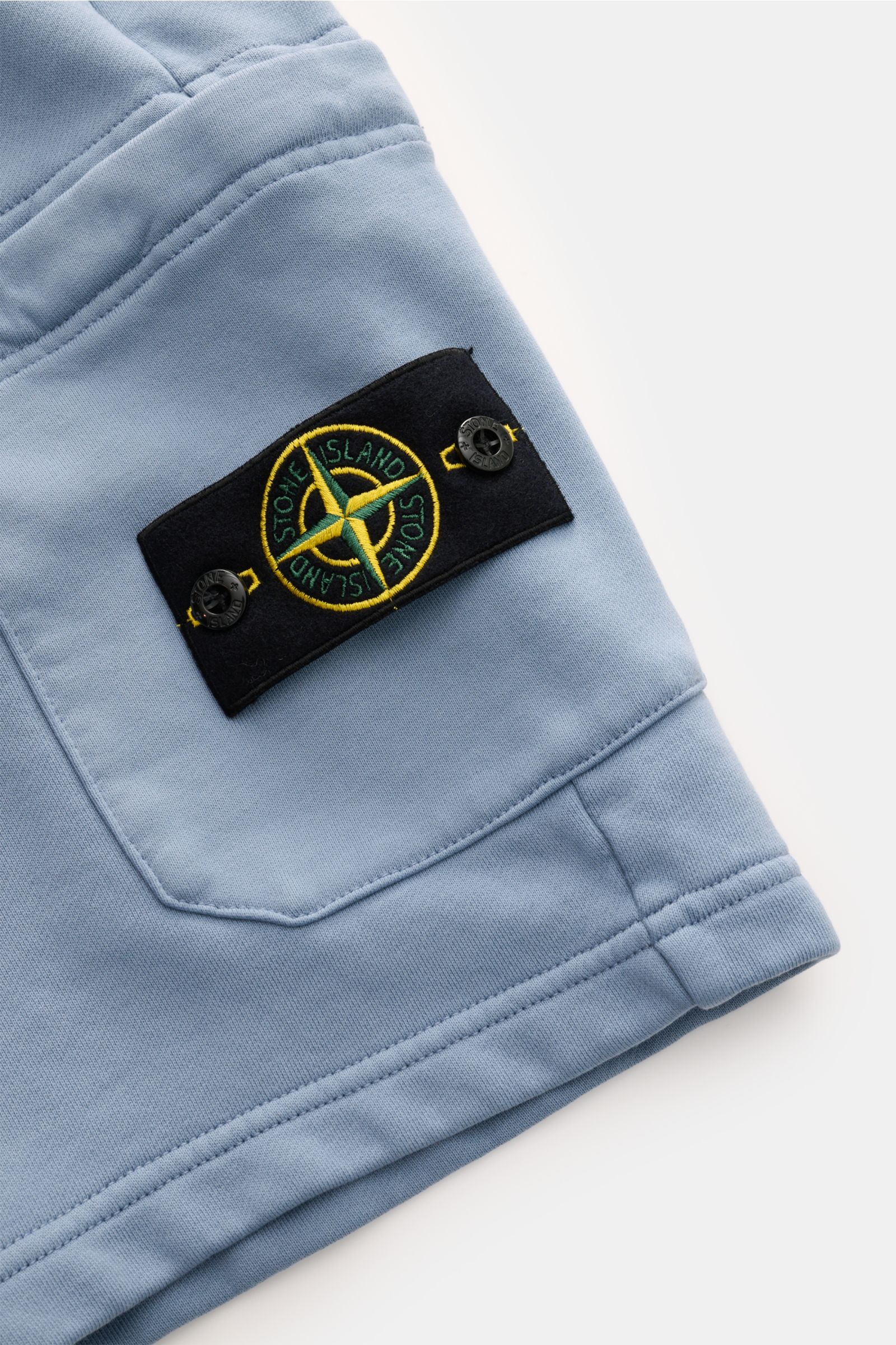 Stone Island Sweatshorts 'Basic Sweat' rauchblau, Detailaufnahme seitlich mit Cargo-Tasche und Kompass-Badge aus Bio-Baumwolle, weicher Griff.