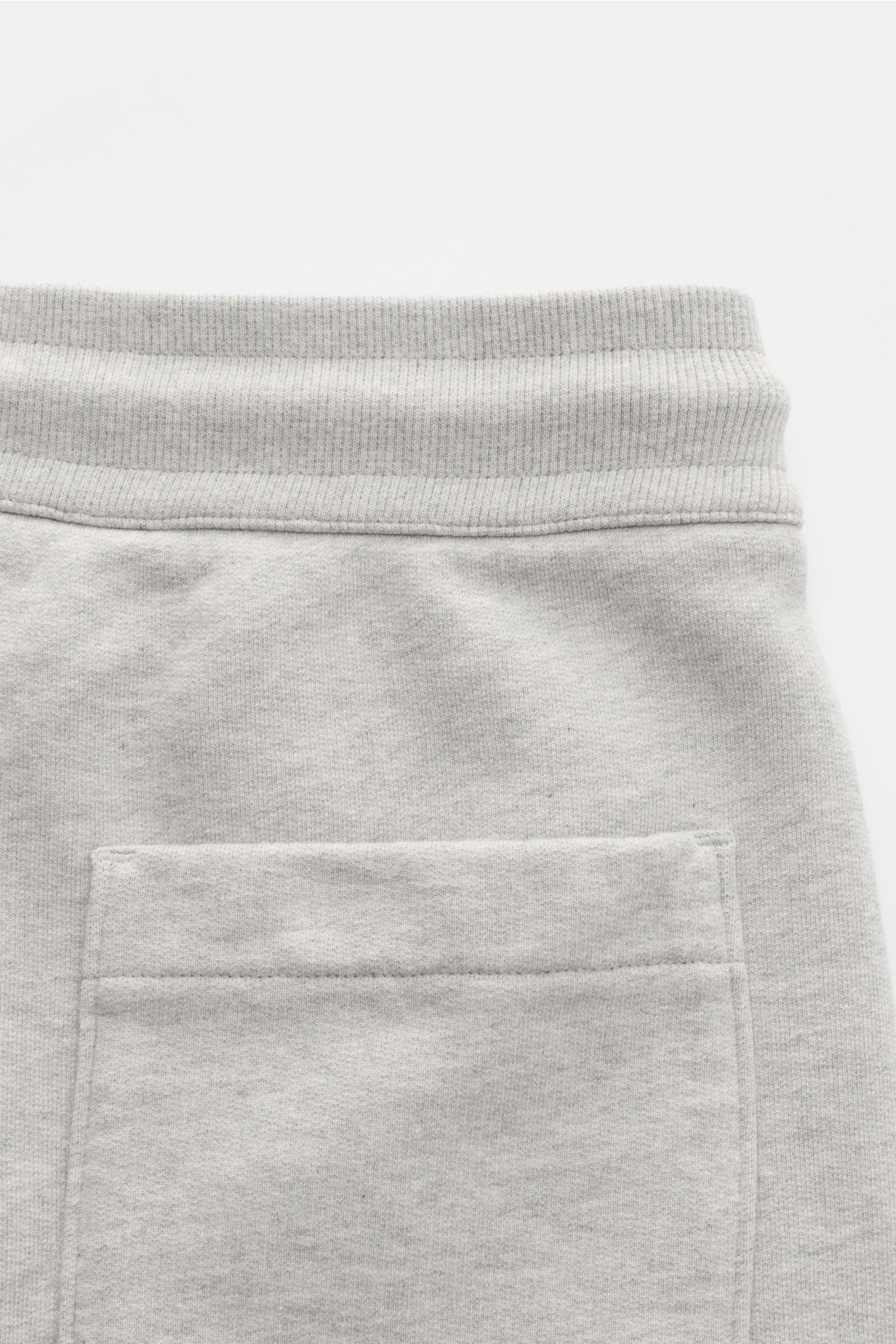 Ami Paris Sweat-Bermudas 'Quota' grau meliert shown from a close-up rear view, featuring an elastic waistband with ribbed texture, a back patch pocket with logo stitching, made of soft, elastic cotton sweat fabric for comfortable wear. Lässig durch die