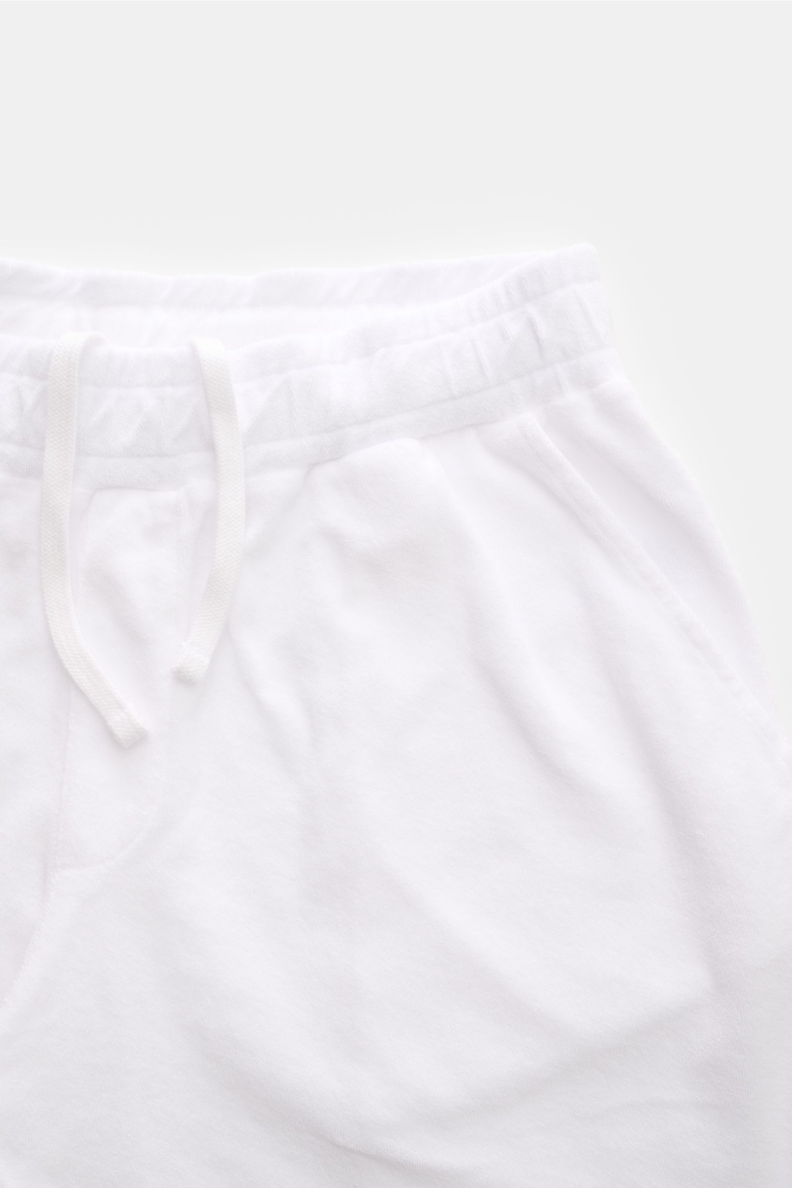 Nahaufnahme der weißen 04651/ A trip in a bag Frottee-Shorts 'Terry' aus weichem Baumwoll-Frottee mit elastischem Bund, Tunnelzug und Taschen, frontal fotografiert.