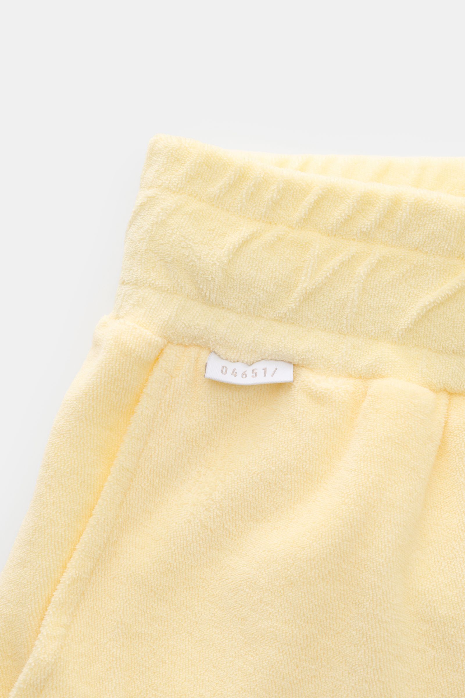 Nahaufnahme von 04651/ A trip in a bag Frottee-Shorts 'Terry' pastellgelb, weicher Baumwoll-Frottee, elastischer Bund mit Tunnelzug, Taschen, kleines Weblabel.