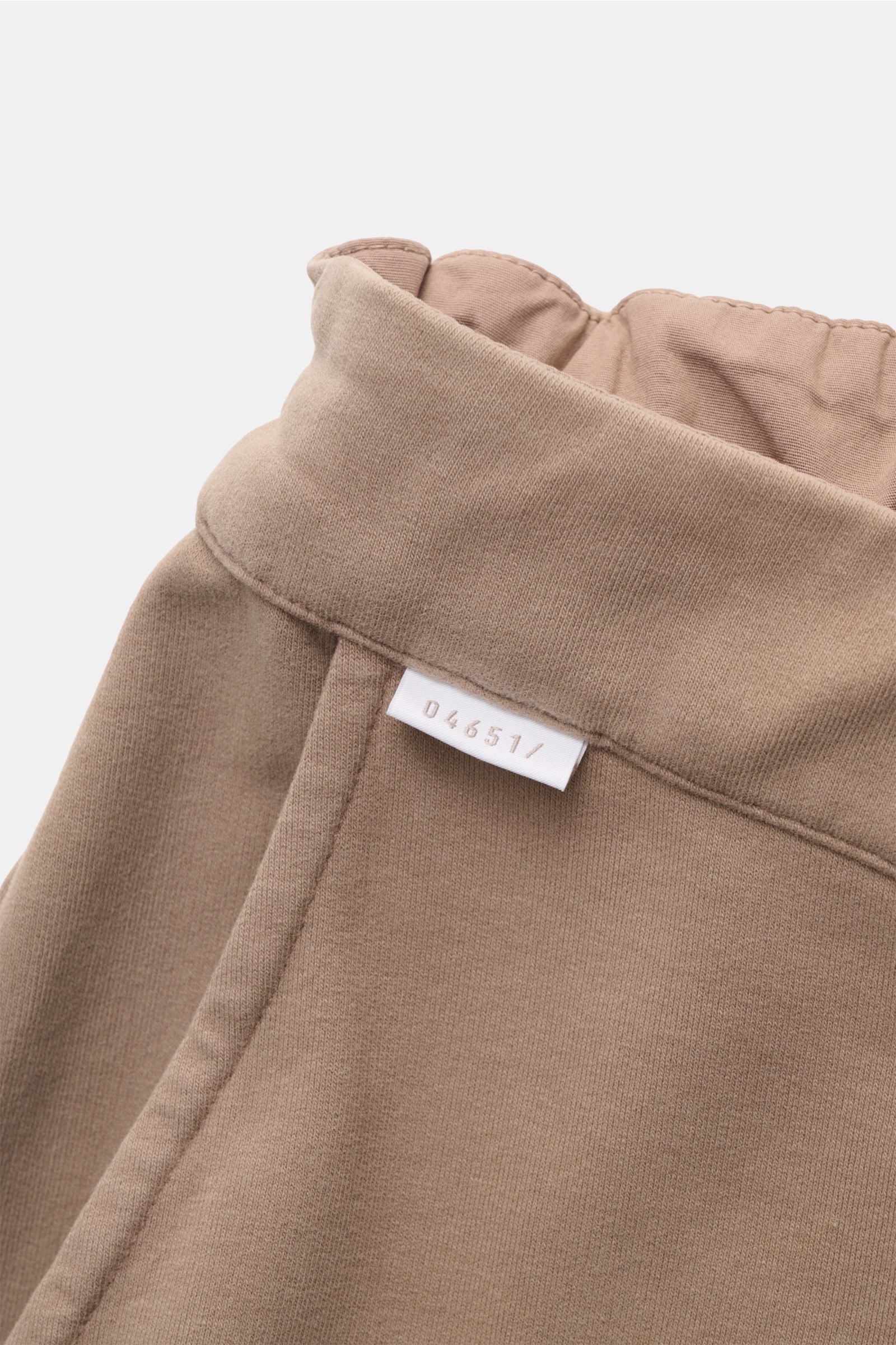 Nahaufnahme der elastischen Bundfalte und des Weblabels der 04651/ A trip in a bag Sweat-Shorts taupe aus Baumwoll-Sweat, Perspektive von oben.