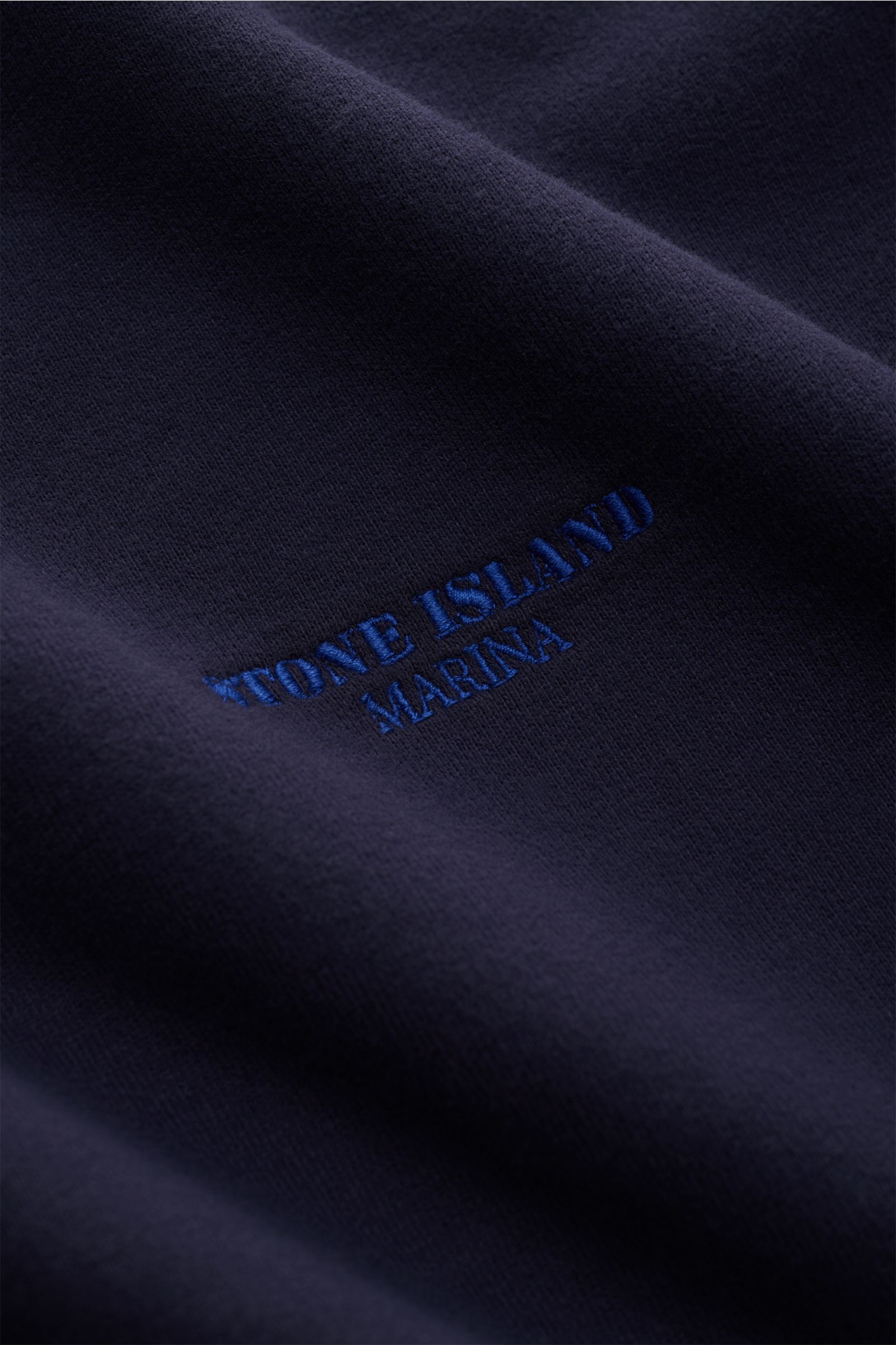Stone Island Sweat-Troyer 'Marina' navy Nahaufnahme von weichem, marineblauem Baumwollstoff mit feinem Stitching und Logo-Stickerei, angeraute Innenseite sichtbar.