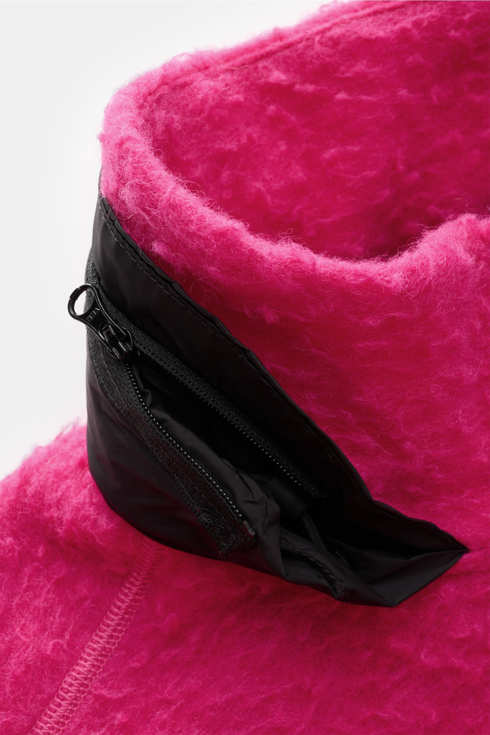 Close-up view of the Stone Island Troyer 'Marina' magenta collar showing its wool-mix fabric, deep zipper, and black pocket details. Extraordinär durch den Herbst: Dieser lässige Troyer aus Woll-Mix in Vintage-Optik von STONE ISLAND mit tiefem Zipper a