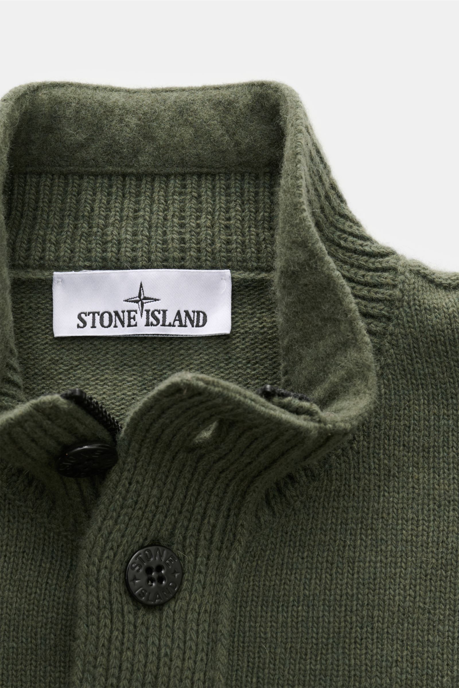 Stone Island Troyer 'Lambswool' oliv, Nahaufnahme von oben, wärmender Wollmix, Troyer-Kragen mit Zipper, geprägte Knöpfe, weicher Griff, Slim Fit, Rippbündchen, Kompass-Badge am Oberarm.