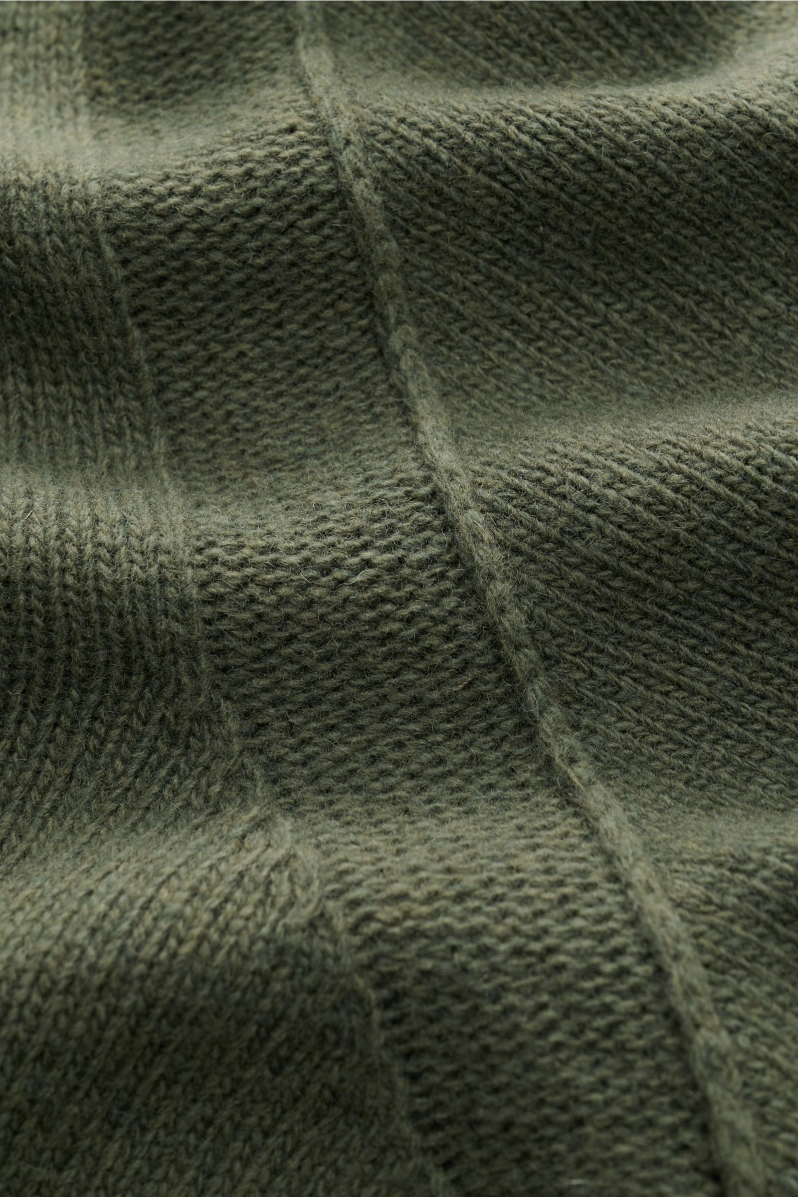 Nahaufnahme des Strickmusters des Stone Island Troyer 'Lambswool' oliv aus Wollmix mit weichem Griff und mittelfeinem Strickbild, fotografiert aus schräger Perspektive.