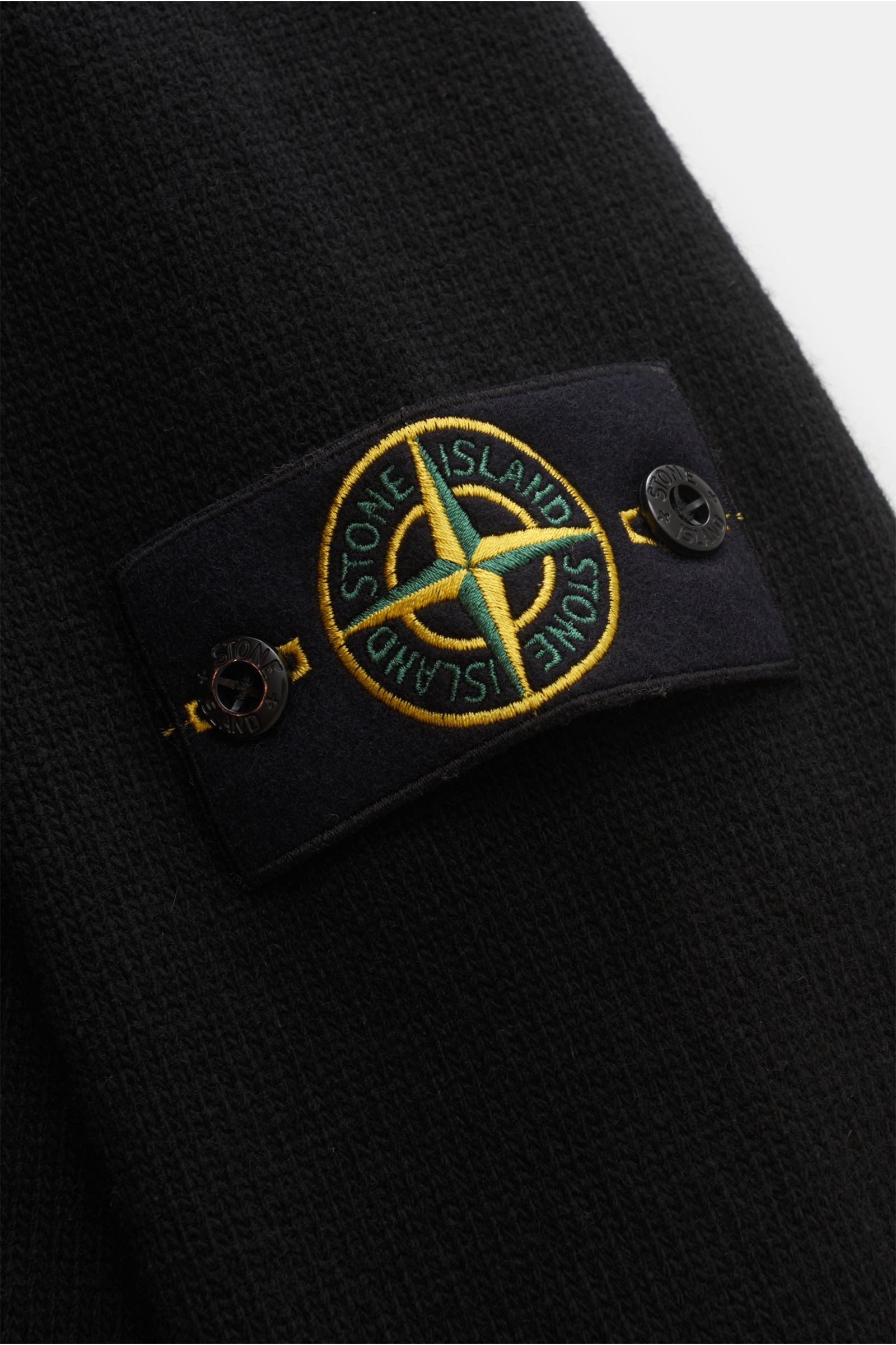 Stone Island Troyer 'Lambswool' schwarz in Nahaufnahme, Fokus auf das markentypische Kompass-Badge am Ärmel aus weichem Wollmix.