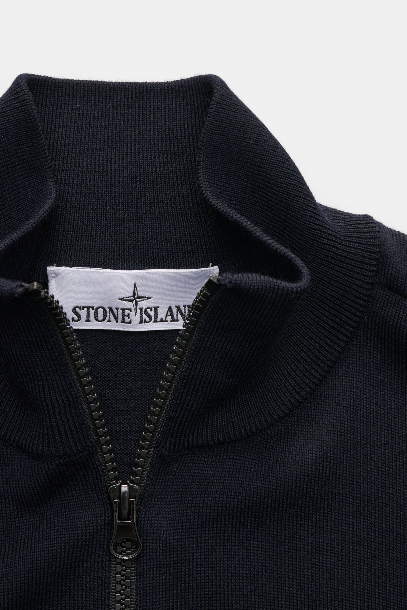 Close-up front view of the Stone Island Troyer 'Light Pure Wool' navy, a slim-fit knit with a ribbed stand collar and zipper, made from pure fine wool with the brand's compass badge on the upper arm. 

Description:  
Ein Strickklassiker mit zeitloser A