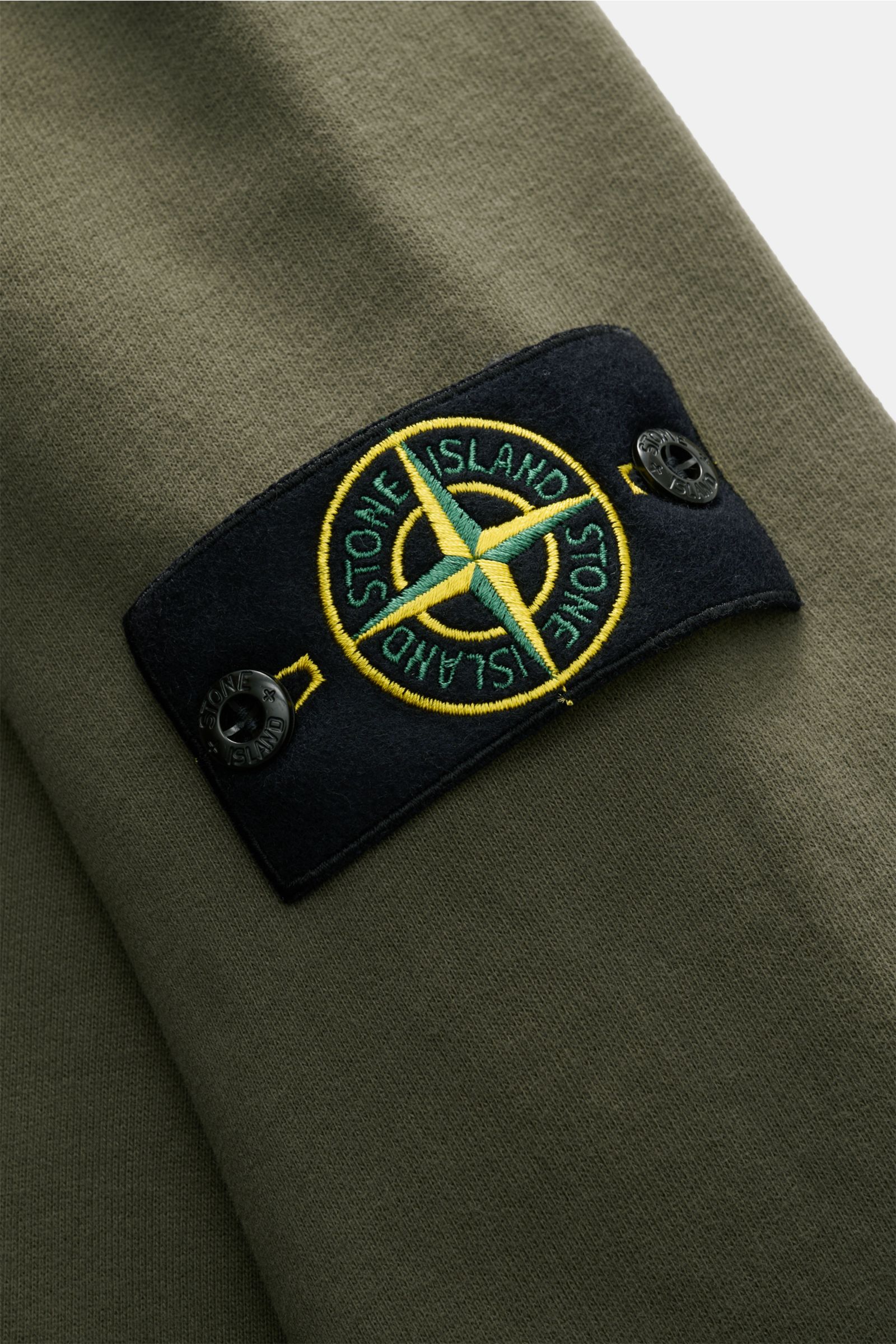 Stone Island Sweat-Troyer oliv in Nahaufnahme von oben, Baumwolle mit angerauter Innenseite, Kompass-Badge am Ärmel sichtbar.