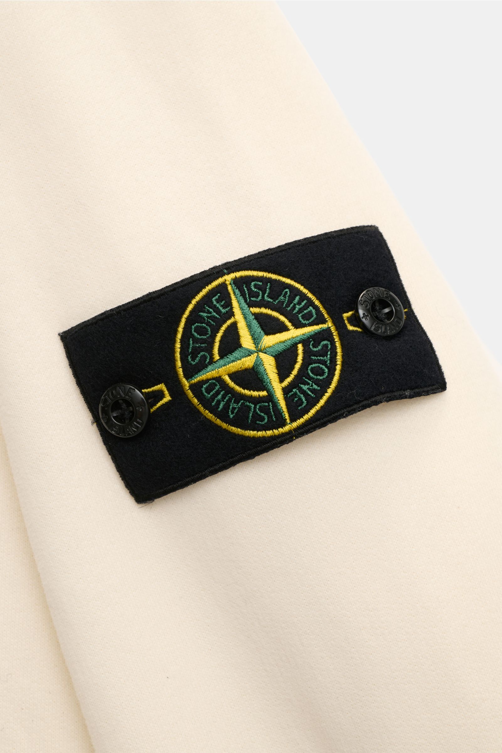 Stone Island Sweat-Troyer creme Nahaufnahme des markentypischen Kompass-Badges auf dem Oberarm aus weichem Baumwoll-Sweat mit Rippstrick-Einsätzen.