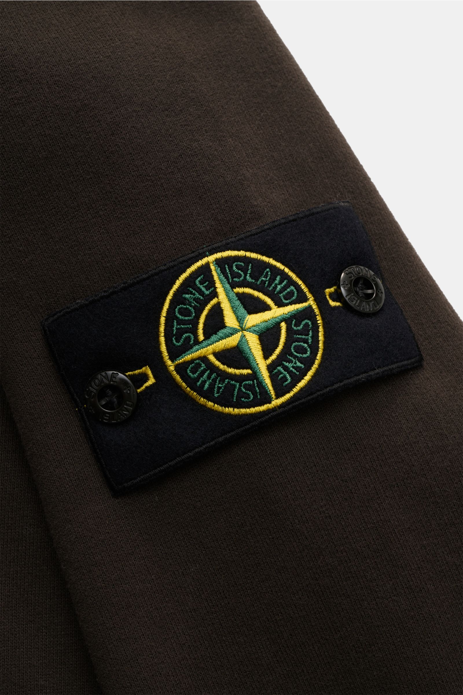 Stone Island Sweat-Troyer graubraun, Detailaufnahme des markentypischen Kompass-Badges am Ärmel aus weichem Baumwoll-Sweat mit Rippstrick.