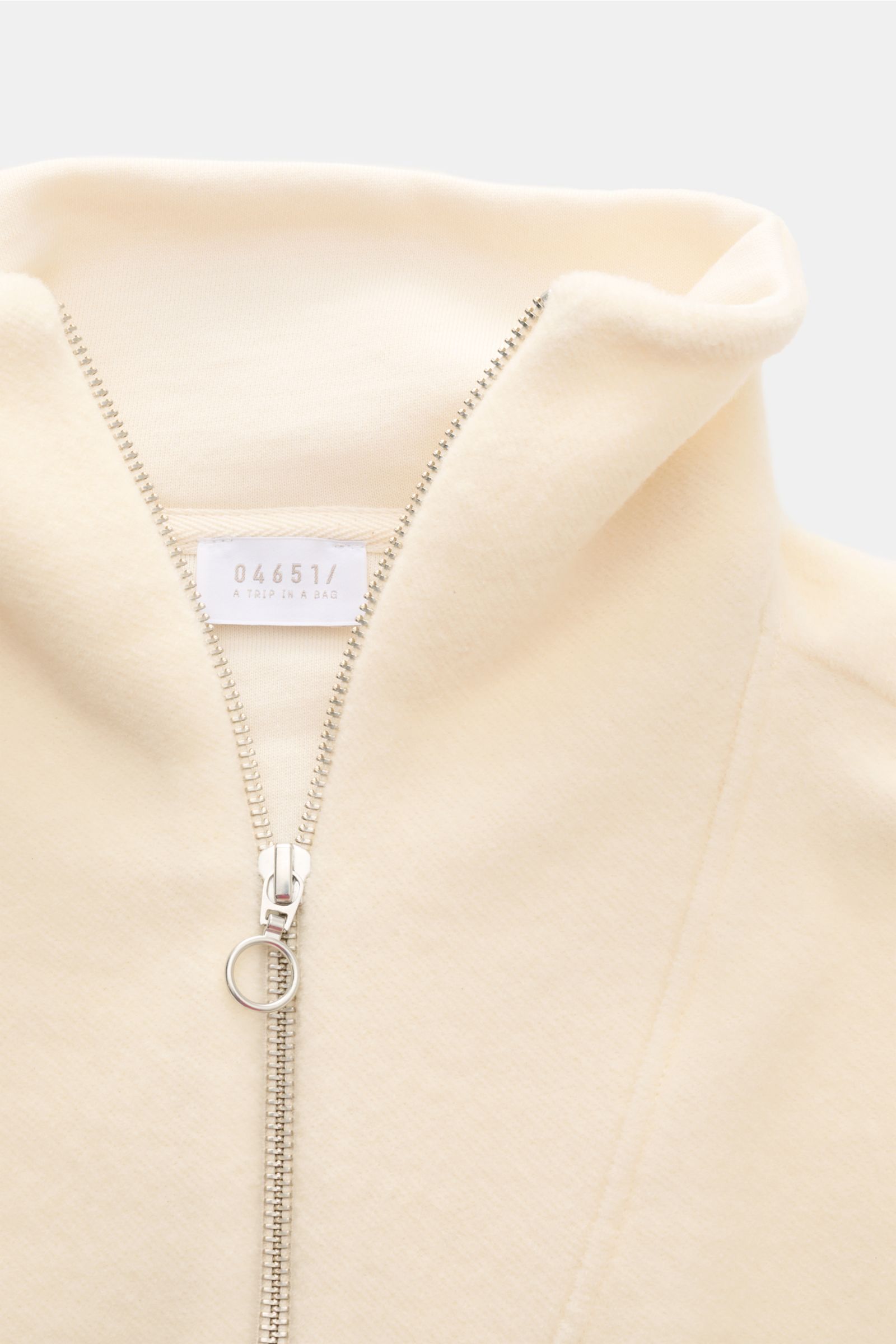 Close-up front view of 04651/ A trip in a bag Troyer 'Cw Quarter Zip' creme with a silver zipper and soft fleece texture, made from a wool-cotton blend. Lässig durch die Übergangszeit: Der Troyer von 04651/ A TRIP IN A BAG überzeugt mit seiner samtigen Fl