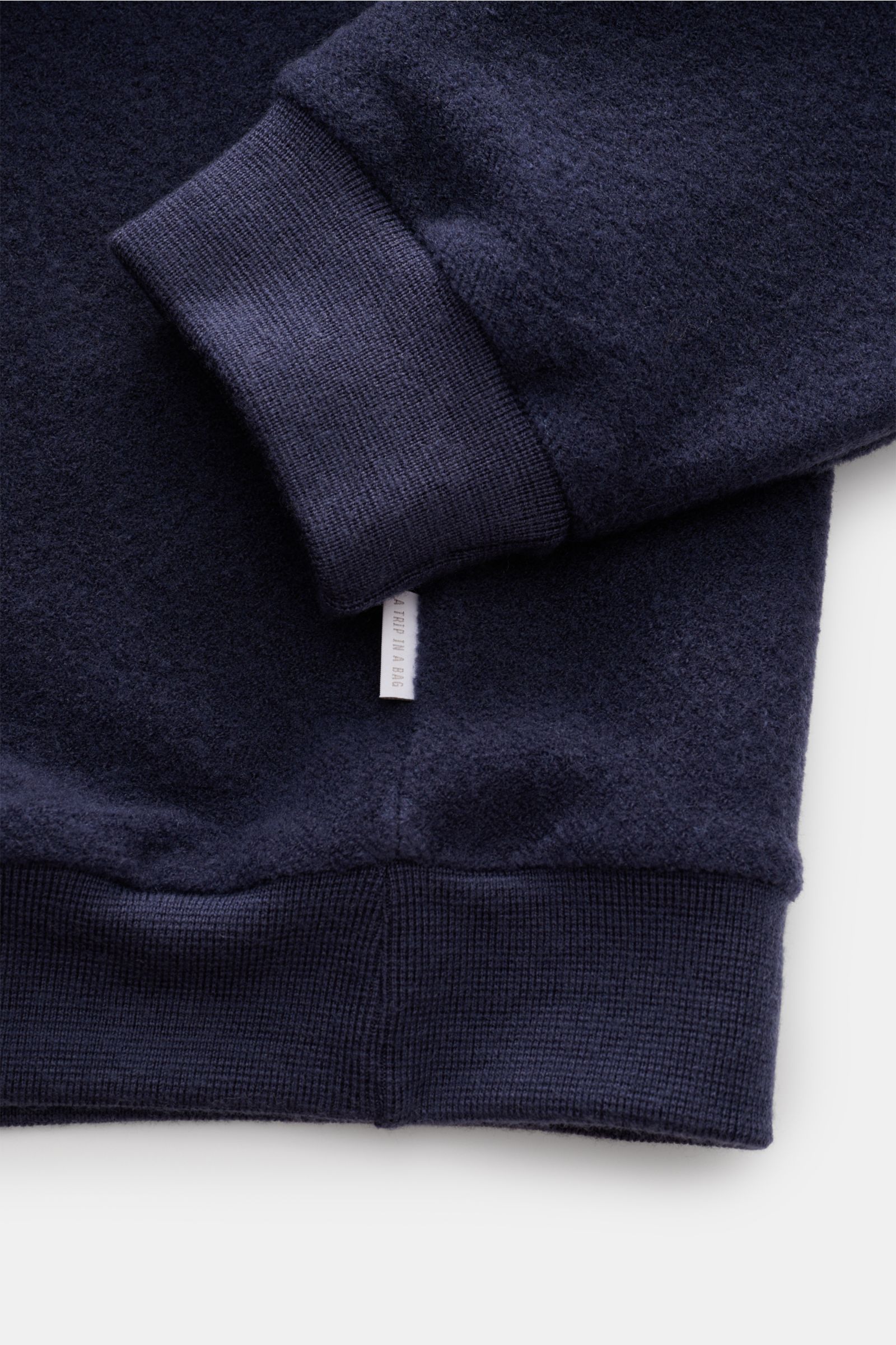 Nahaufnahme des dunkelblauen 04651/ A trip in a bag Troyer 'Cw Quarter Zip' mit weichem Fleece, Rippbündchen und Weblabel in Seitennaht.