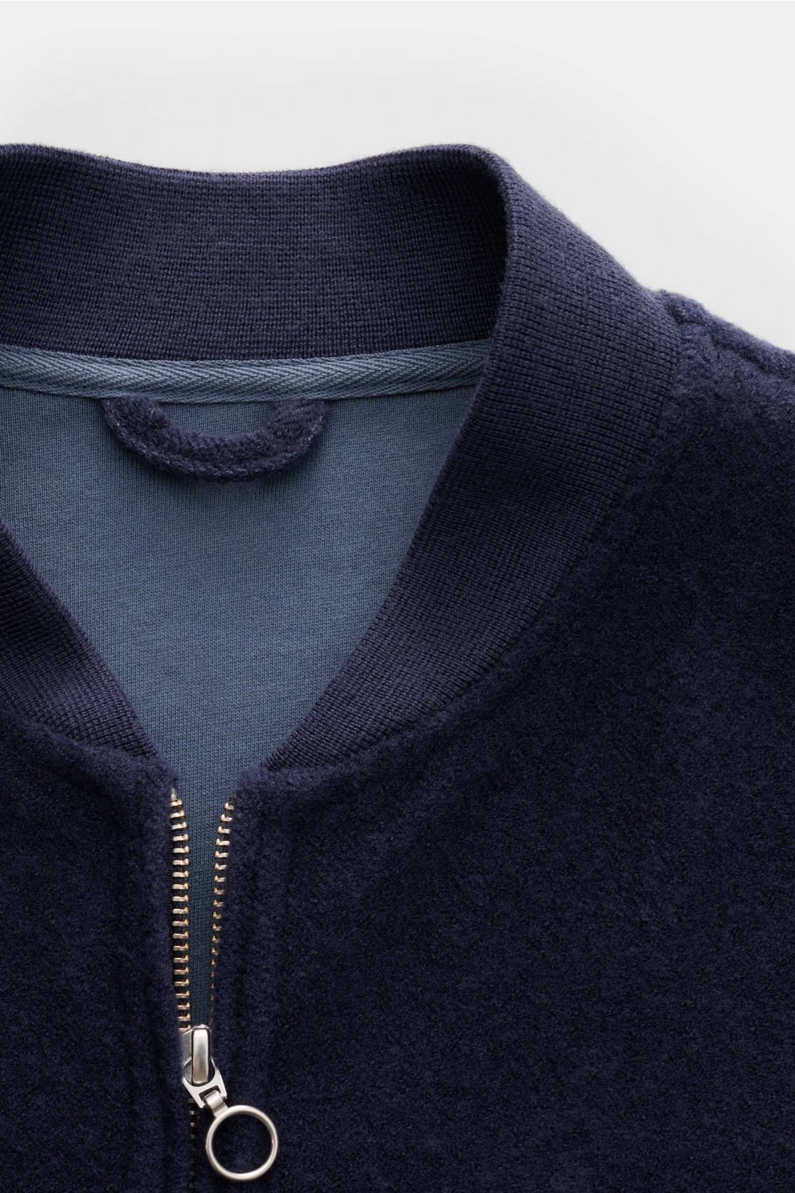 Close-up front view of 04651/ A trip in a bag Blouson dunkelblau with ribbed collar, two-way zipper, and soft wool-cotton fleece texture. Lässig durch die Übergangszeit: Der Blouson von 04651/ A TRIP IN A BAG überzeugt mit seiner samtigen Fleece-Textur au