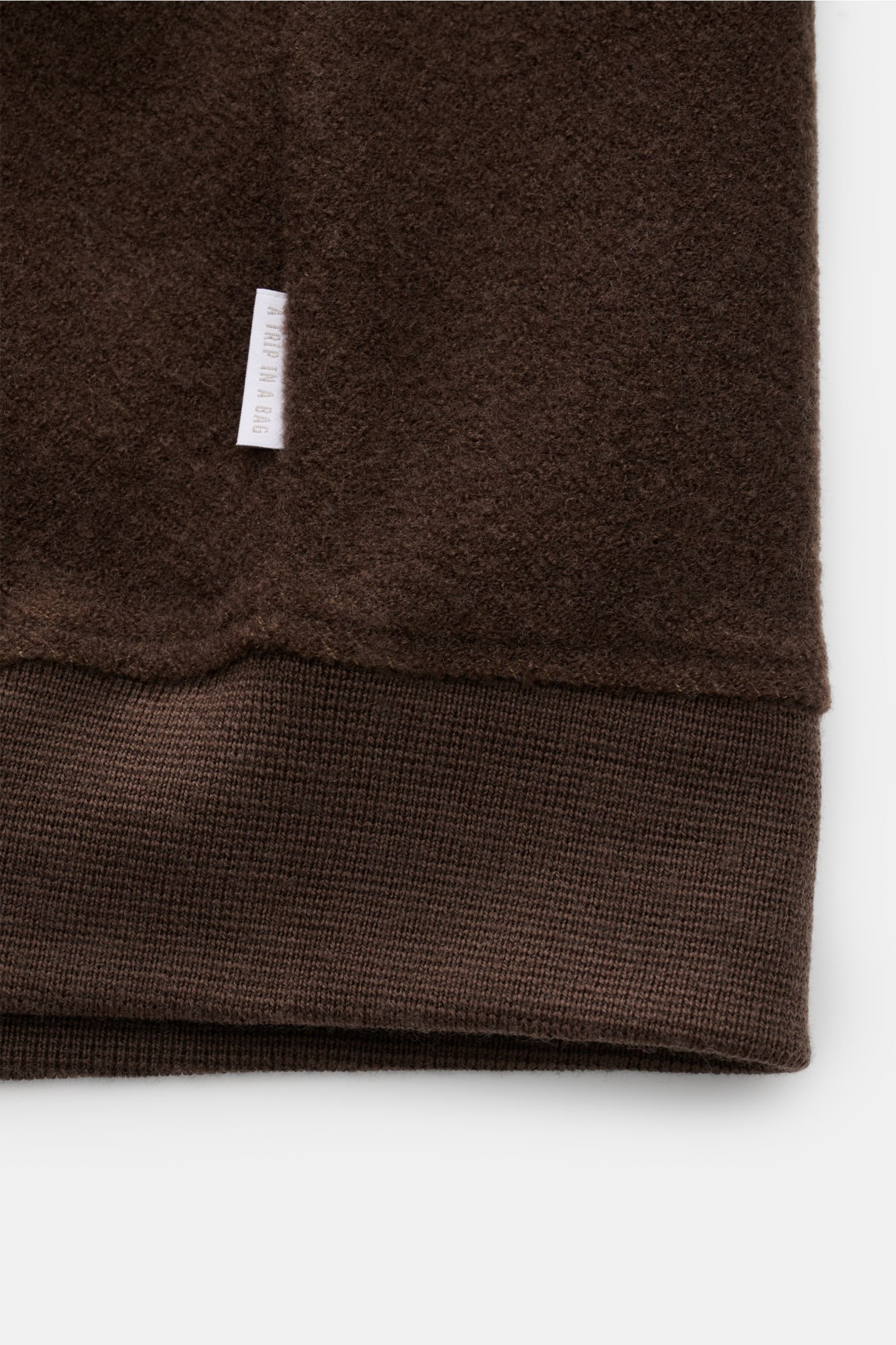 Brauner Detail-Ausschnitt des 04651/ A trip in a bag Blouson dunkelbraun mit samtiger Fleece-Textur, Rippbündchen und Weblabel in Seitennaht.