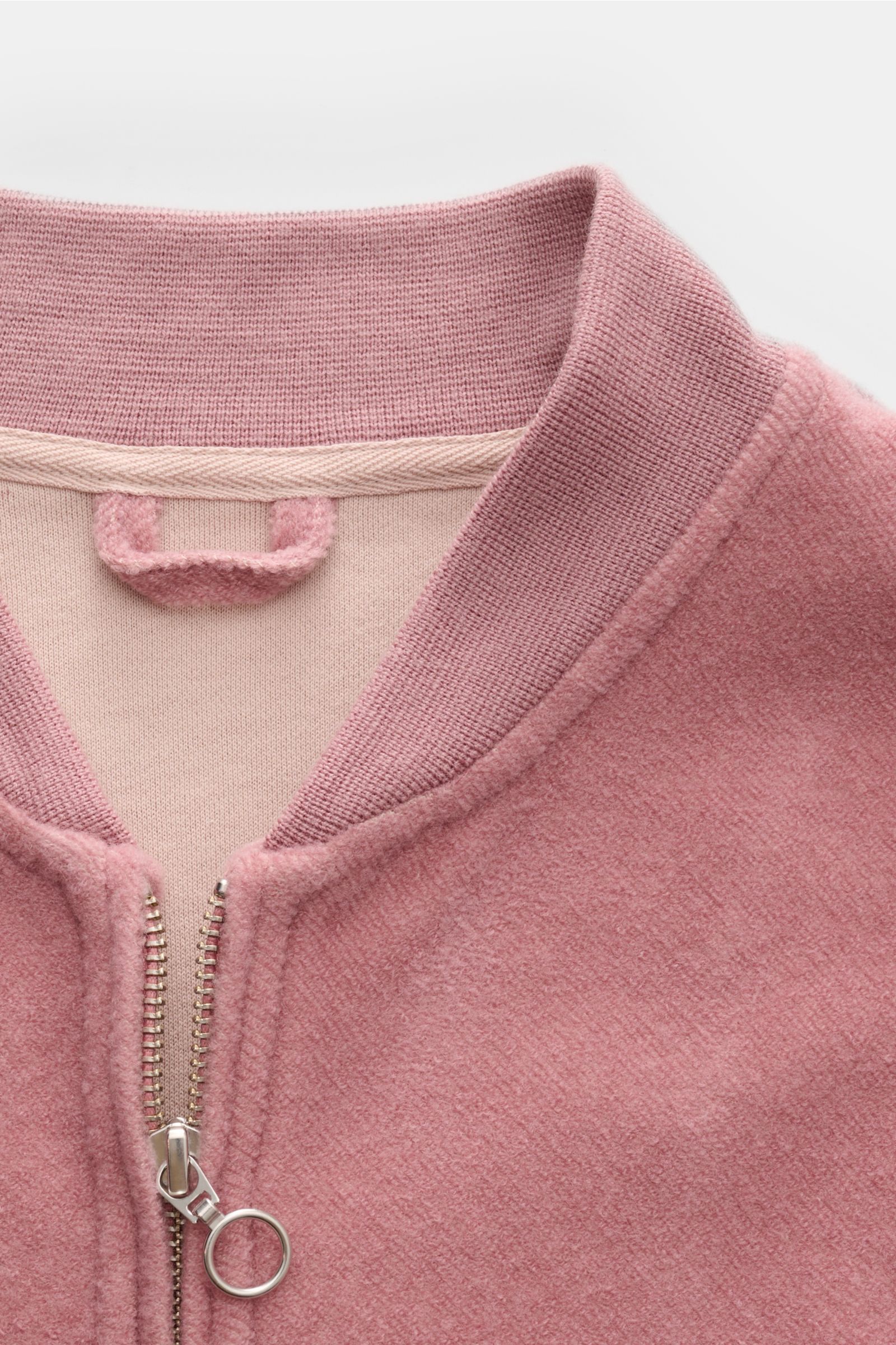 Close-up front view of the 04651/ A trip in a bag Blouson altrosa, showcasing its soft fleece texture, ribbed collar, and silver two-way zipper. Lässig durch die Übergangszeit: Der Blouson von 04651/ A TRIP IN A BAG überzeugt mit seiner samtigen Fleece-Te