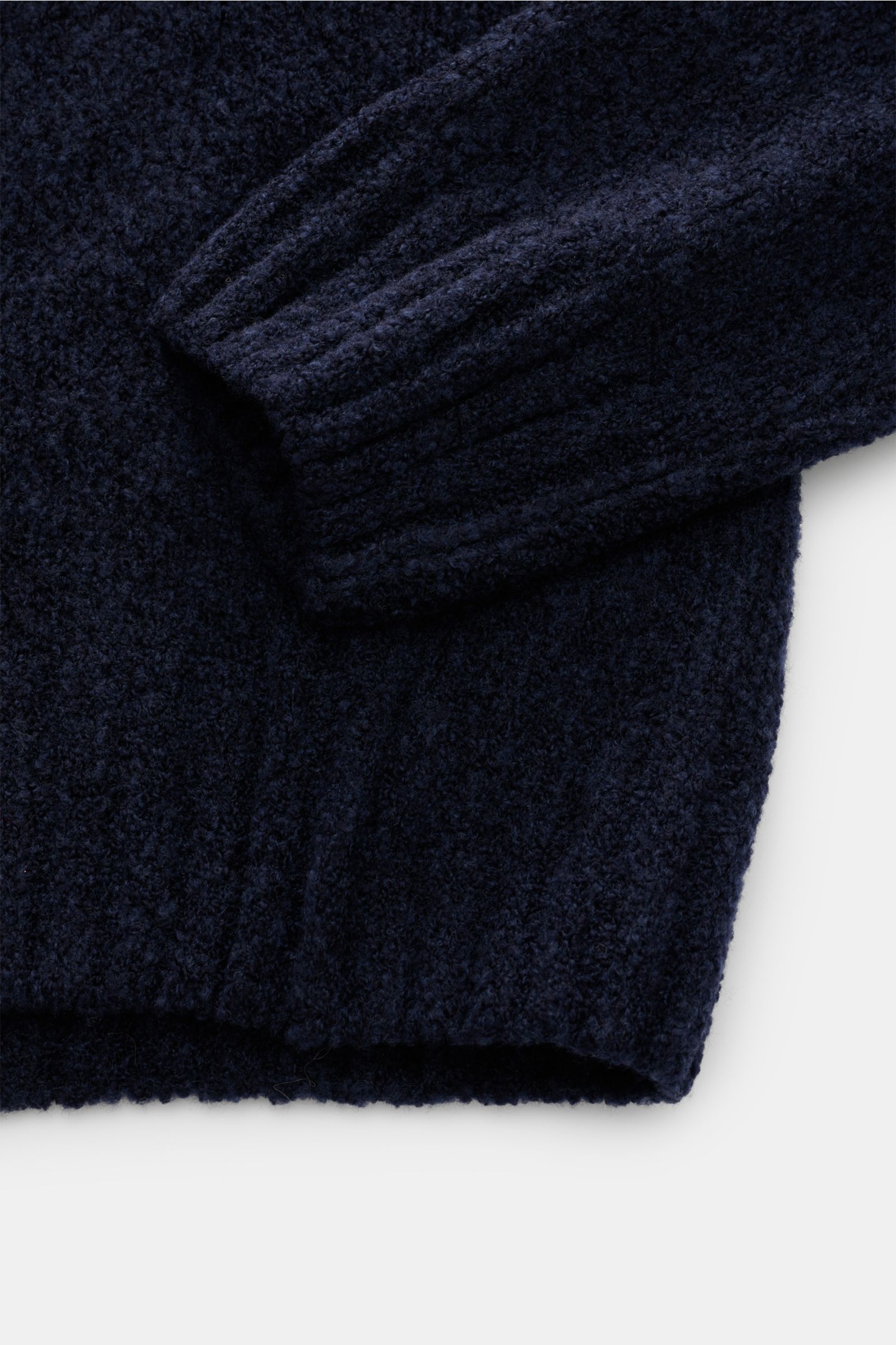 Close-up view of the sleeve and bottom hem of the 04651/ A trip in a bag Half-zip jumper 'Grainy' navy, showing its blend of wool and microfibre, soft feel, bouclé knit, medium-fine knit, regular fit, high rib knit collar with zip, and wide ribbed bands.